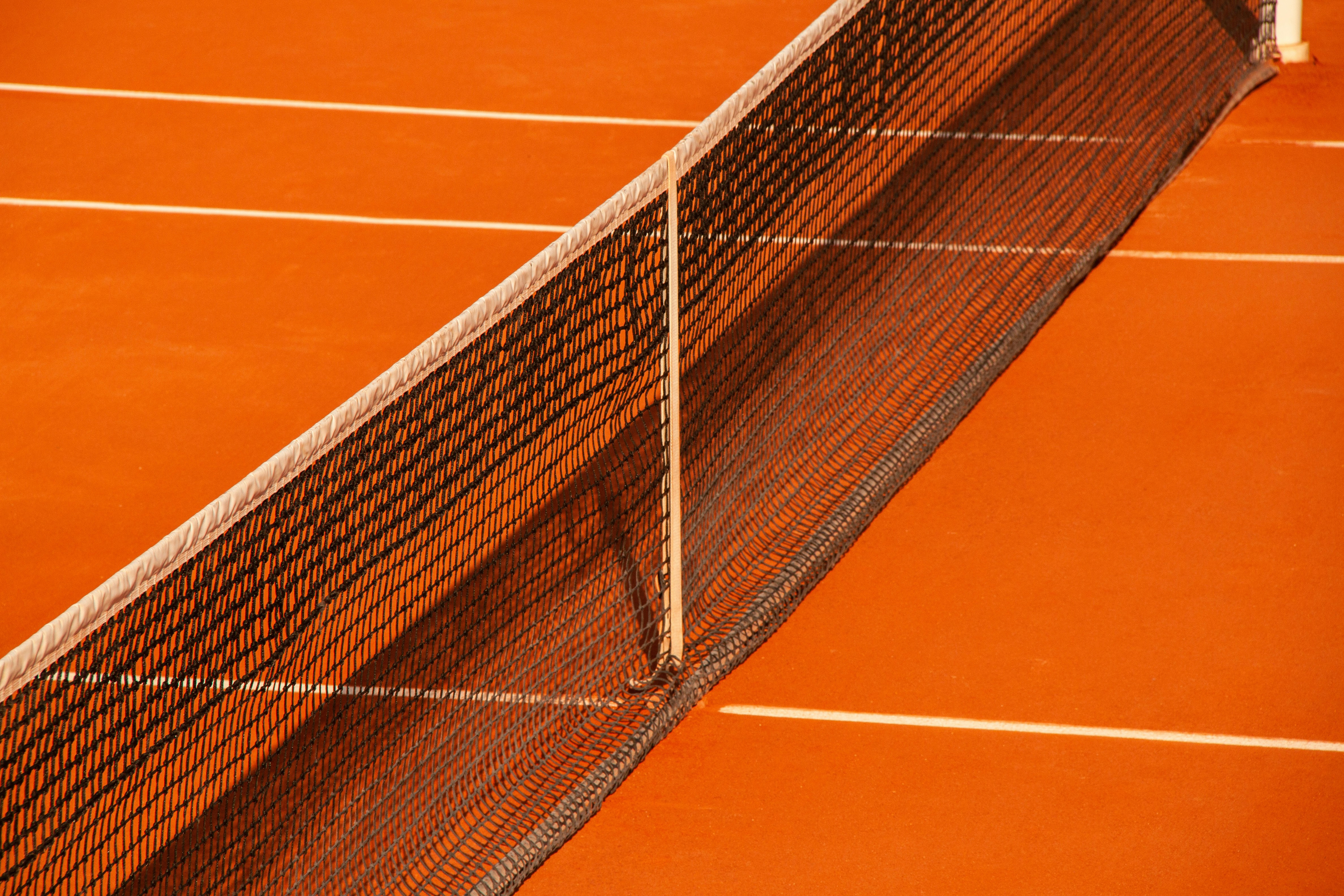 Tennis court net and lines in the sunlight.