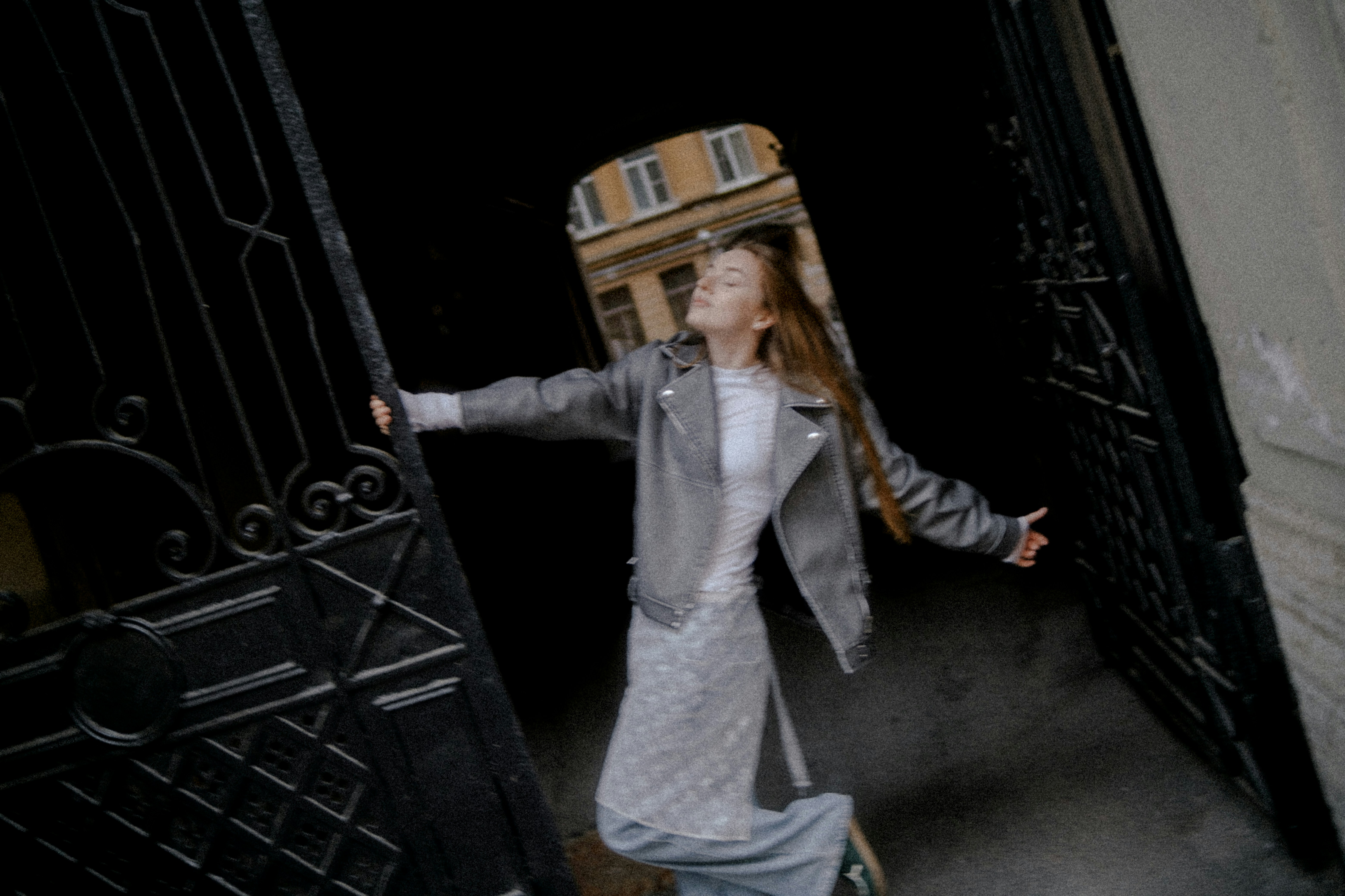 Woman in jacket opens large ornate gates