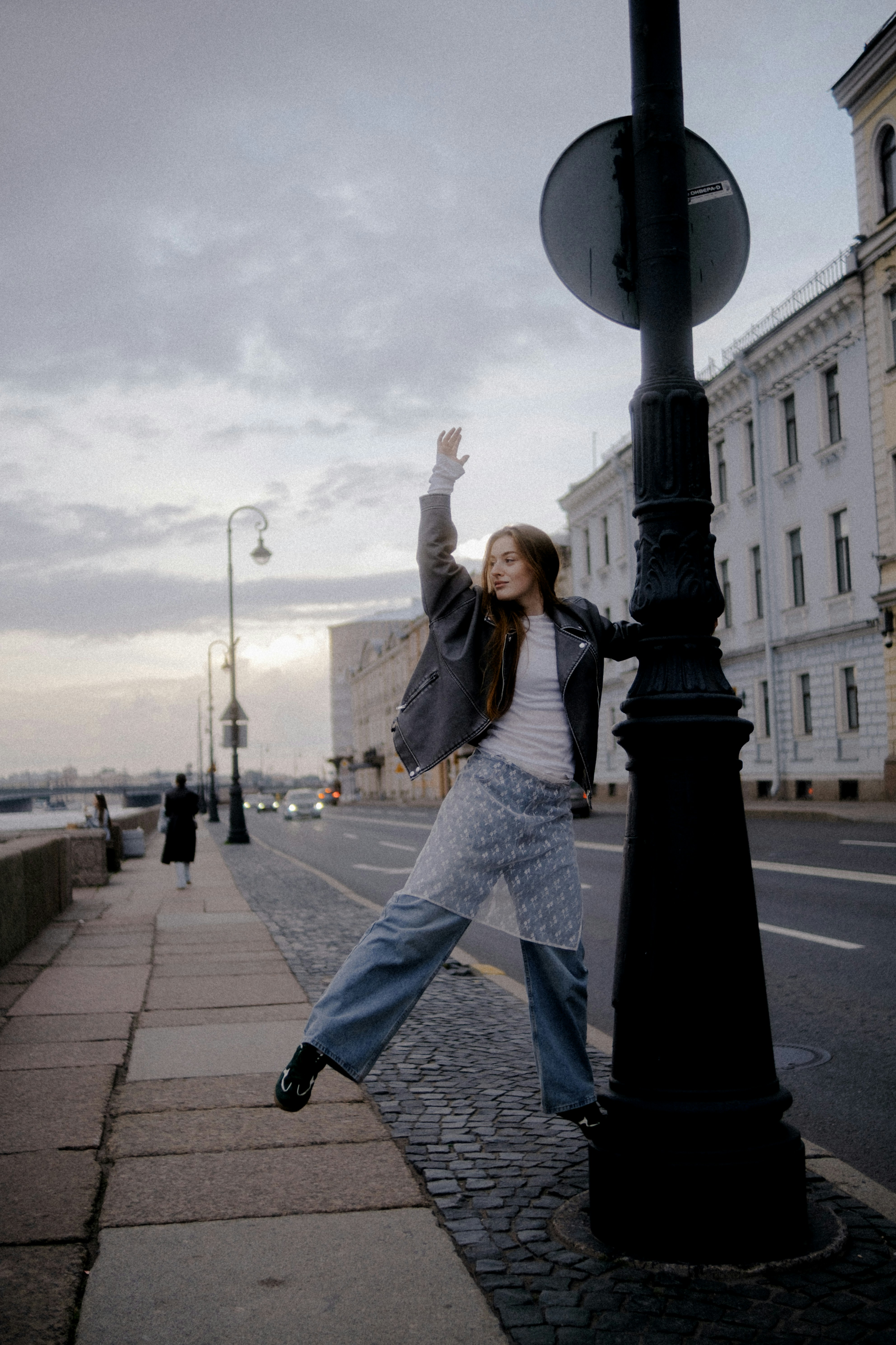 Woman posing by lamppost on city street