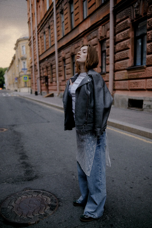 Persona con chaqueta oversize y pantalón ancho en una calle empedrada