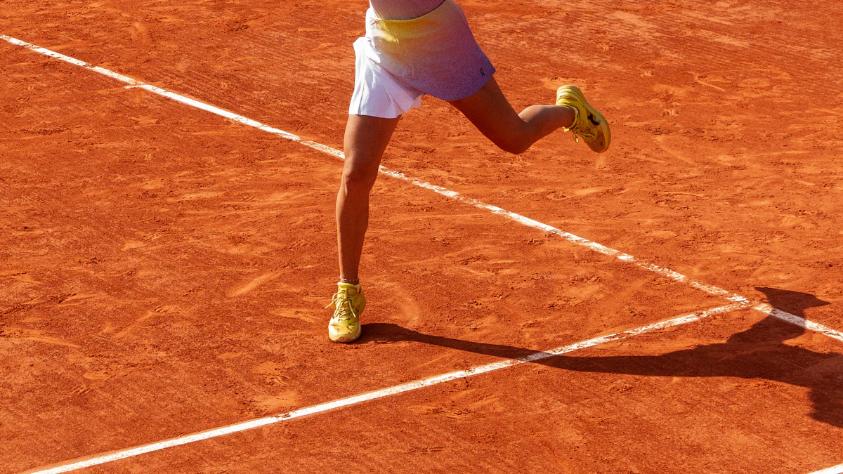 A tennis player sliding across a red clay court