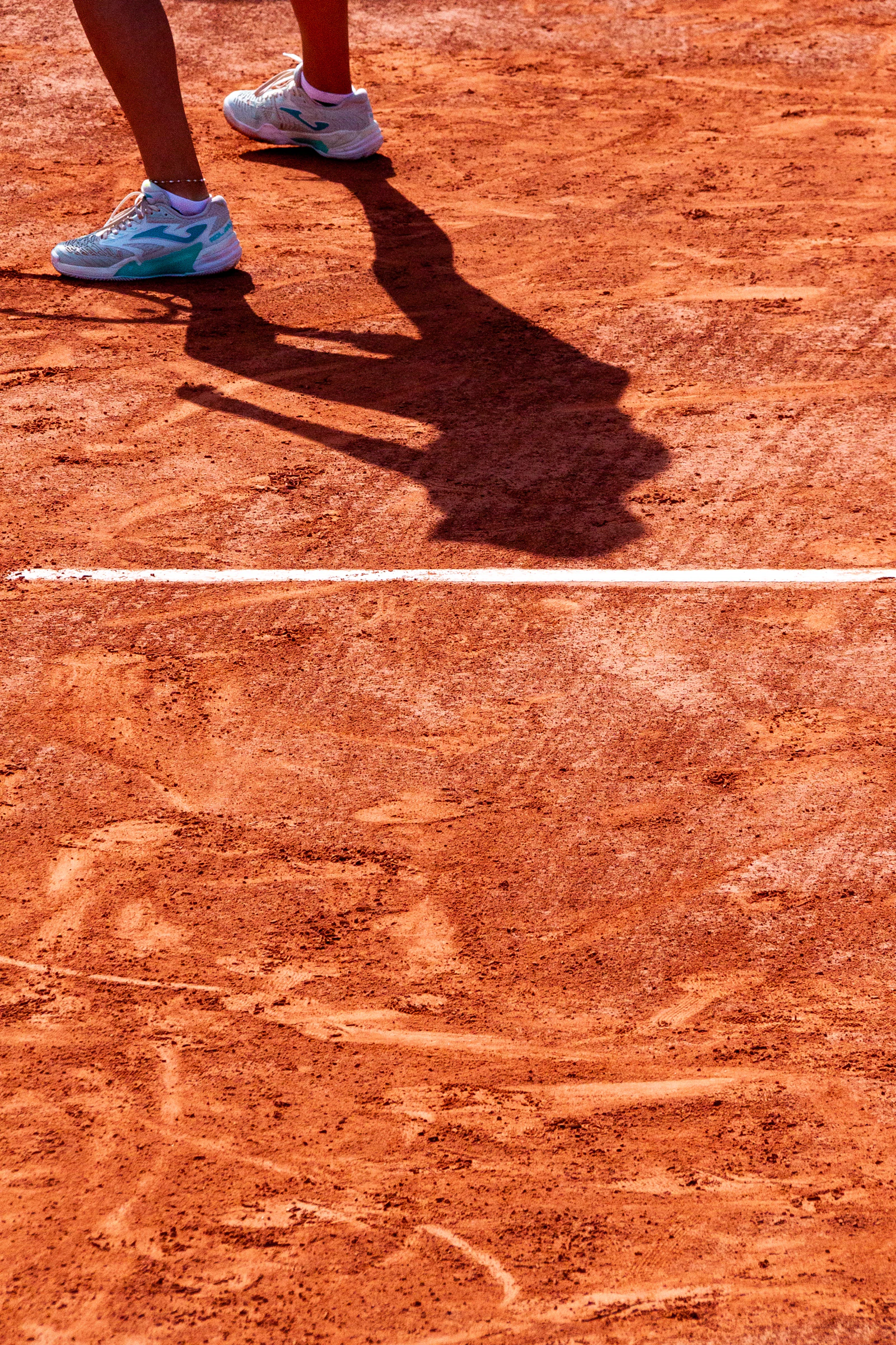 Tennis shoes and shadow on the clay court