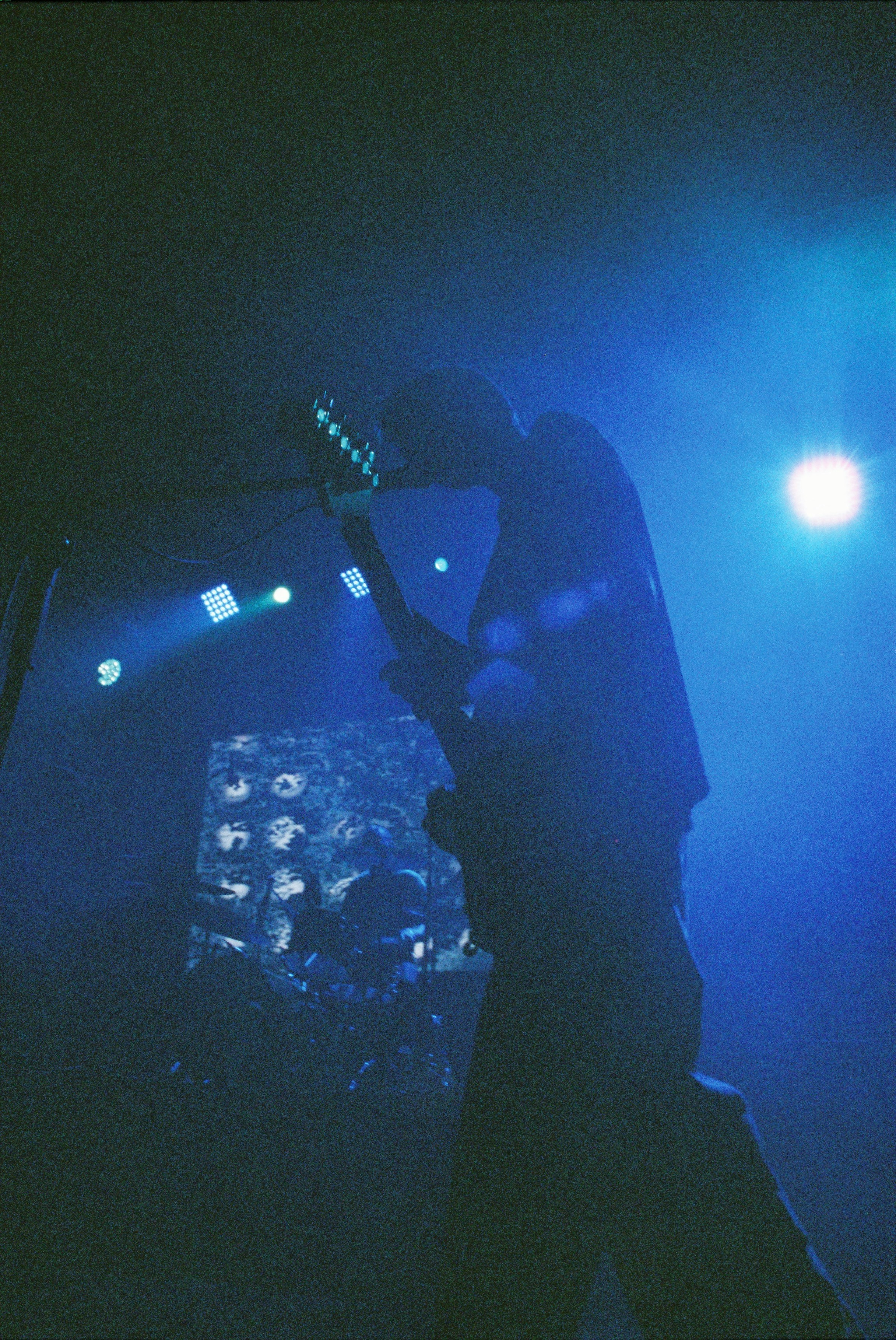 A guitarist plays on stage, silhouetted in blue.