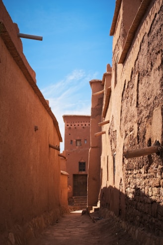 A narrow alleyway reveals moroccan architecture in sunlight.