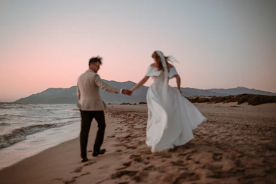 Newlyweds run along the beach at sunset.