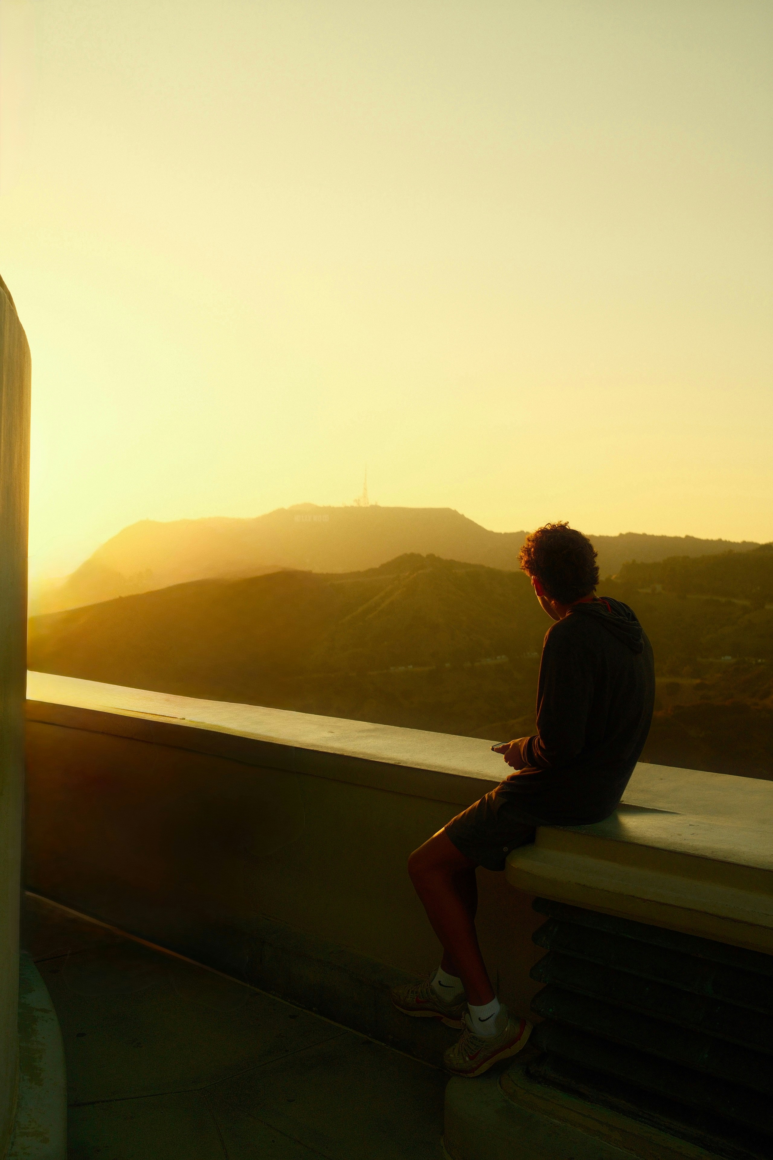 L’homme est assis, profitant d’une vue sur les montagnes au coucher du soleil.