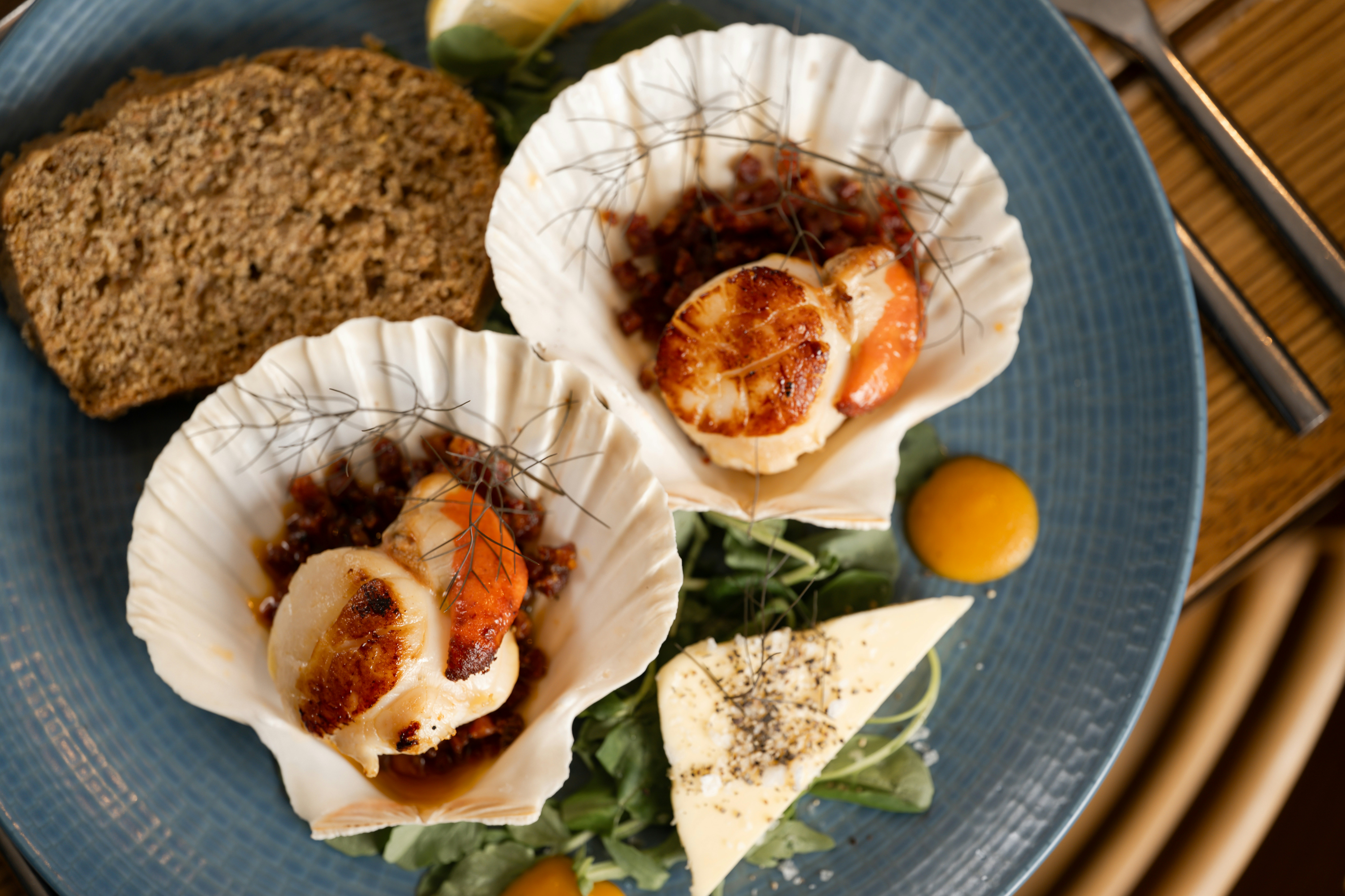 Seared scallops are served in shells with bread.