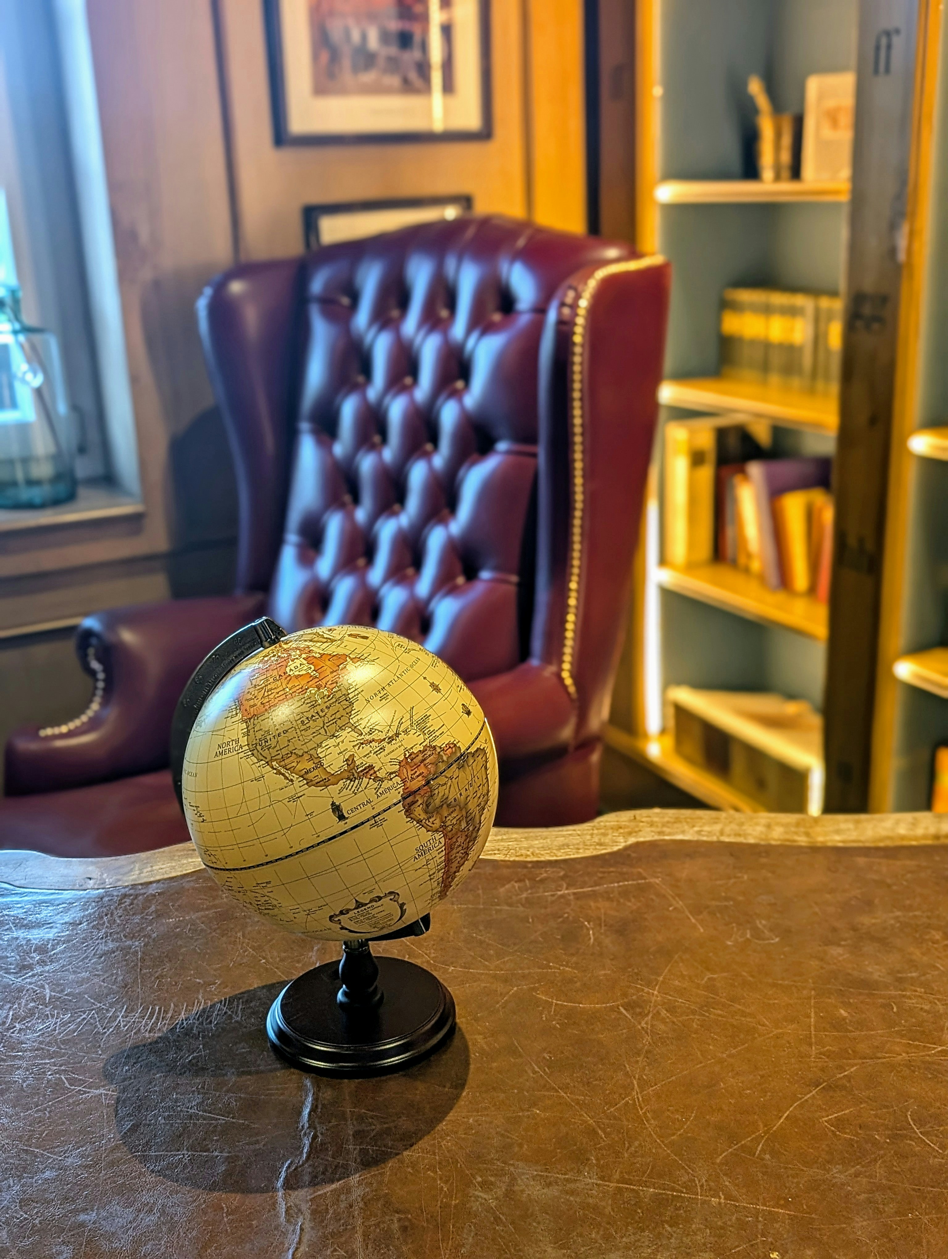 A globe sits on a desk in a study.