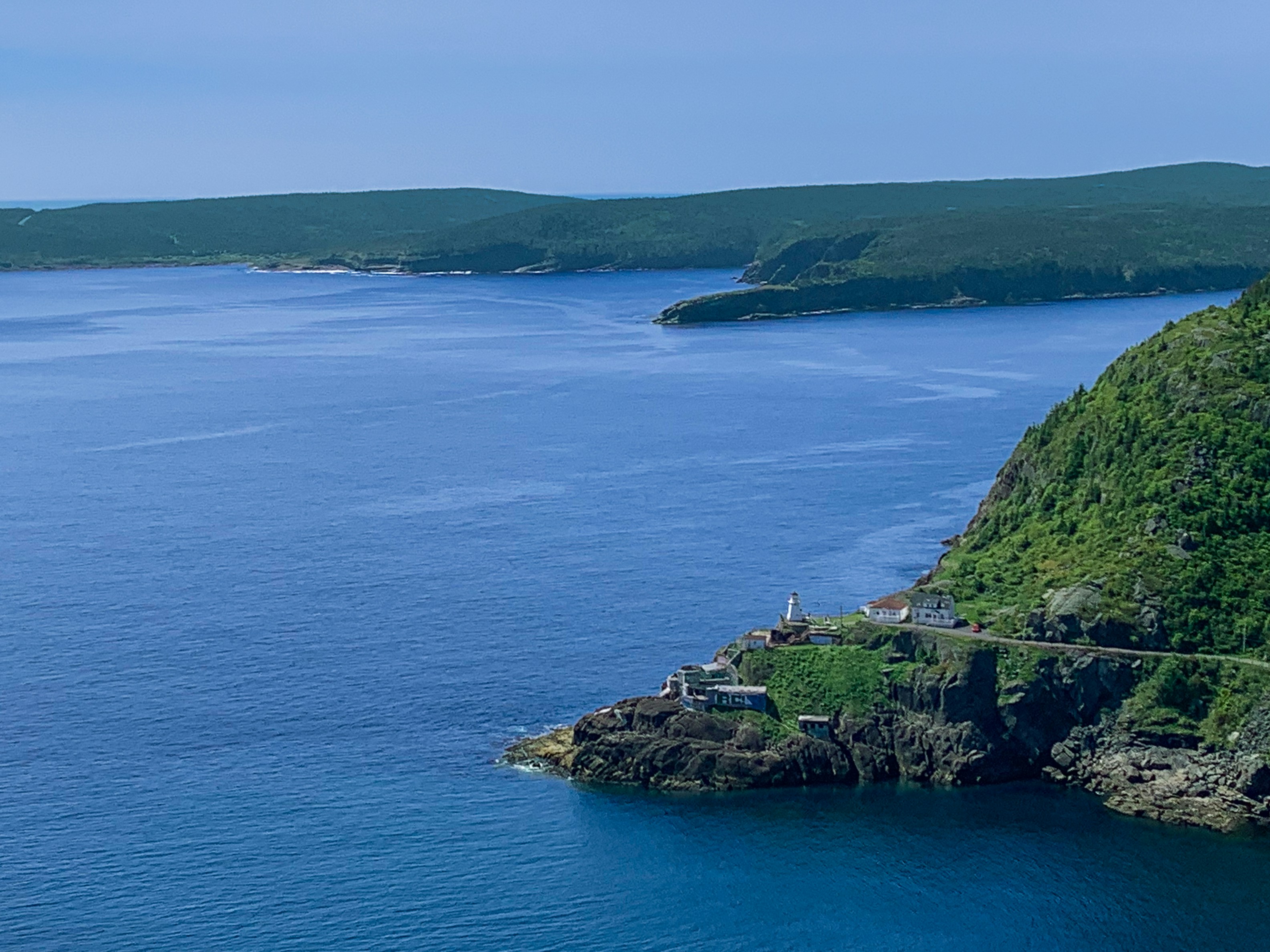 The ocean meets land with lush green hills.