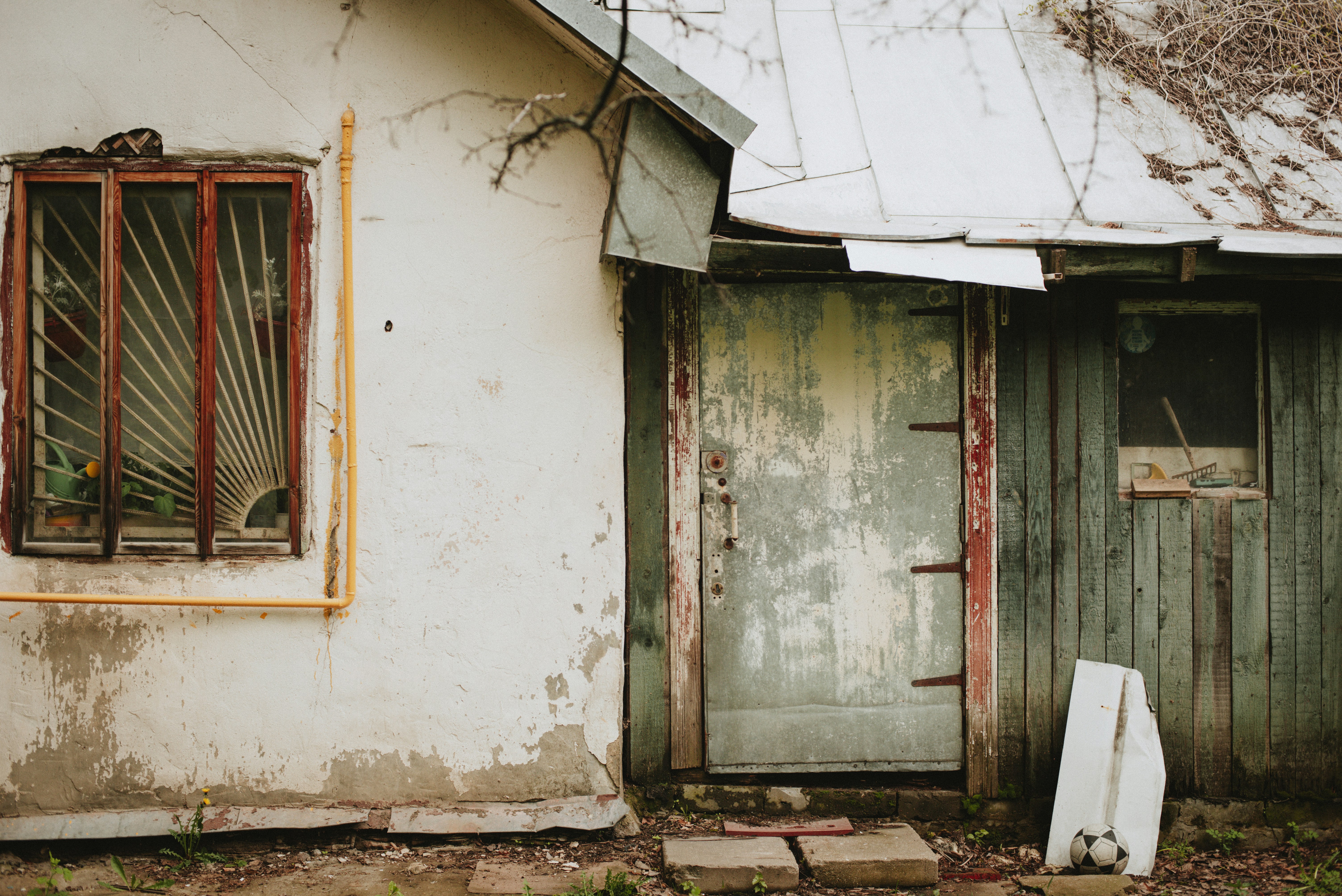 Old, weathered building with damaged windows and door.