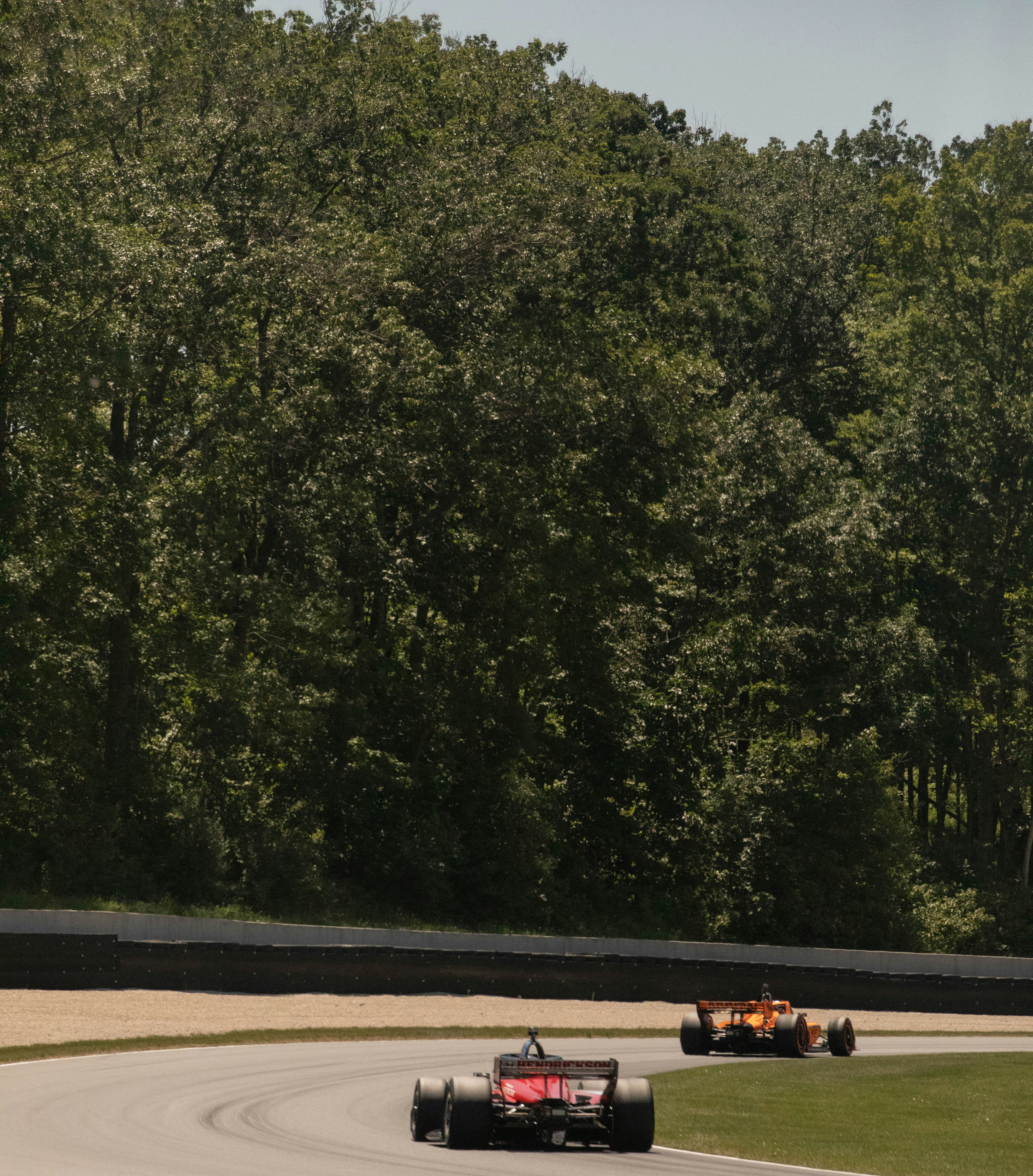 Two race cars speed around a curved track.