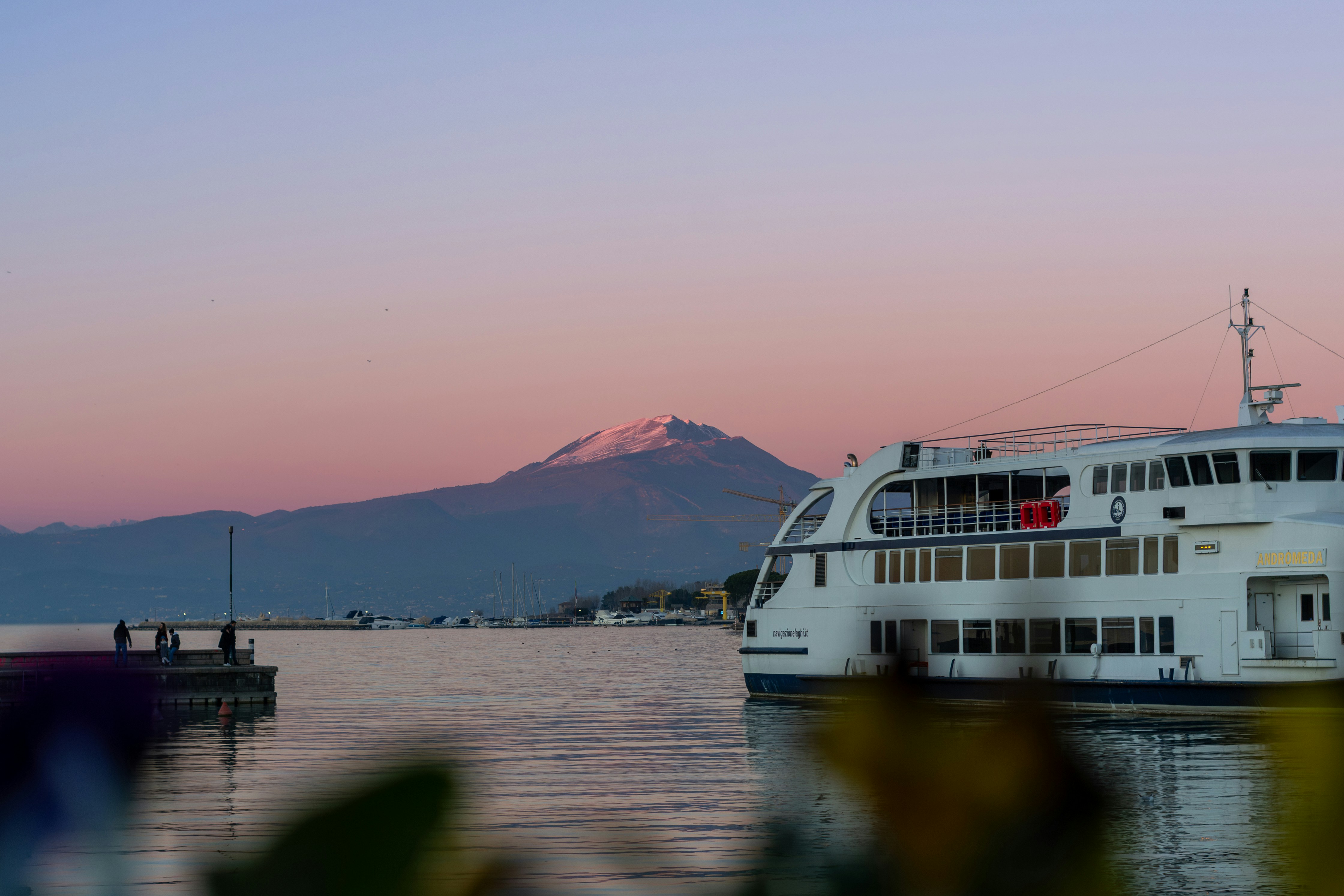 A ferry boat sits on the water near a mountain.