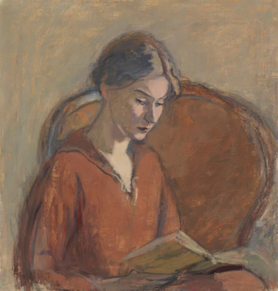 A young woman reading a book in a chair.
