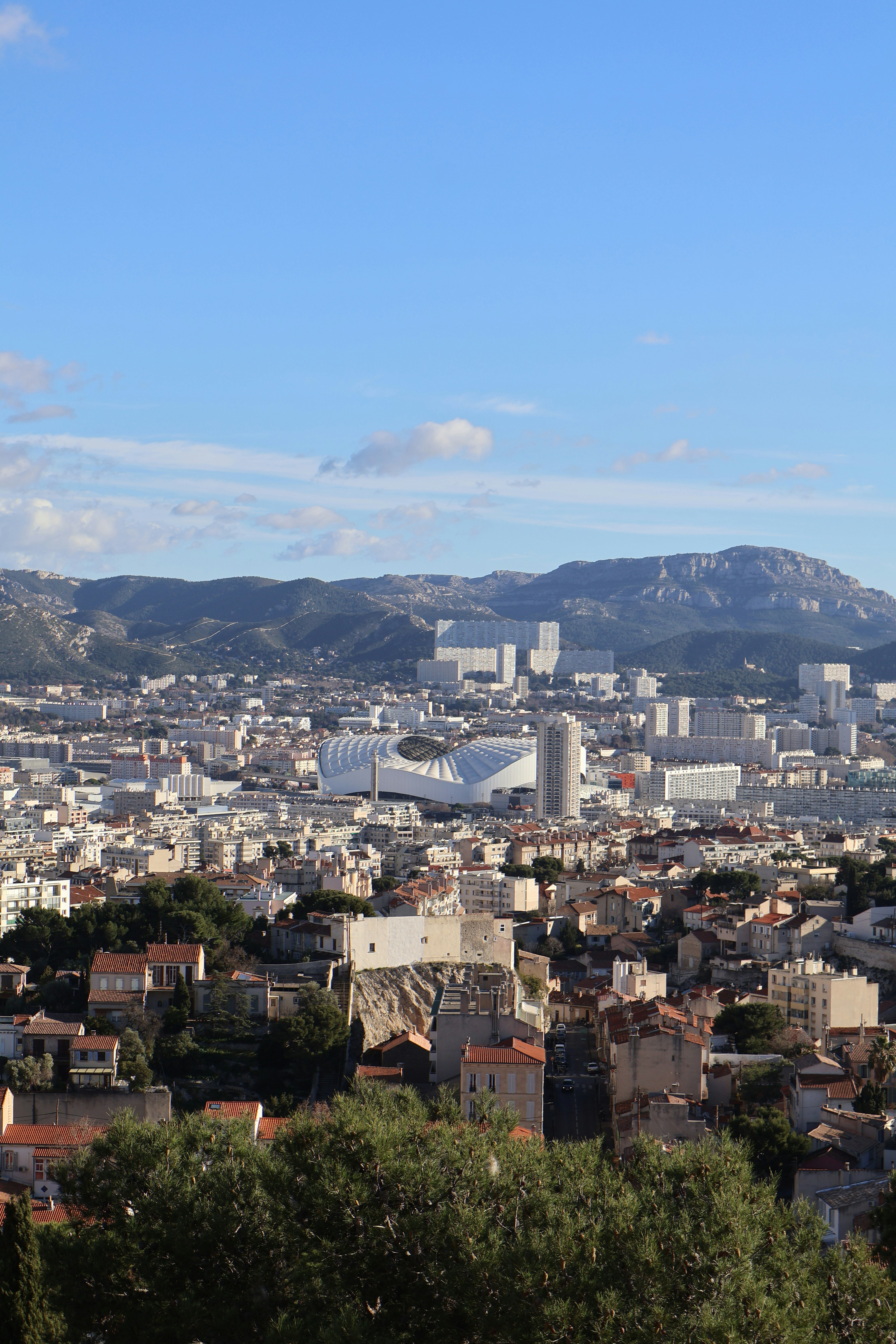 A cityscape shows buildings, mountains, and clear skies.