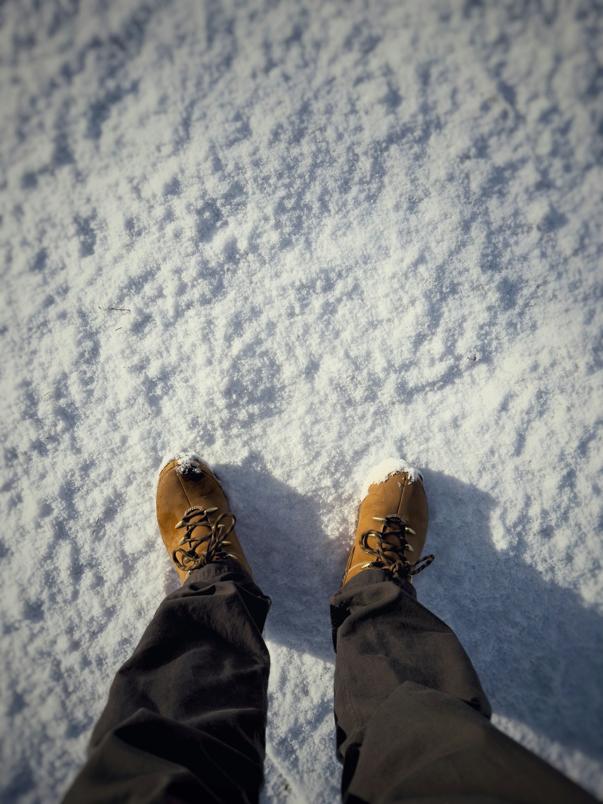 Boots and legs stand in fresh snow.