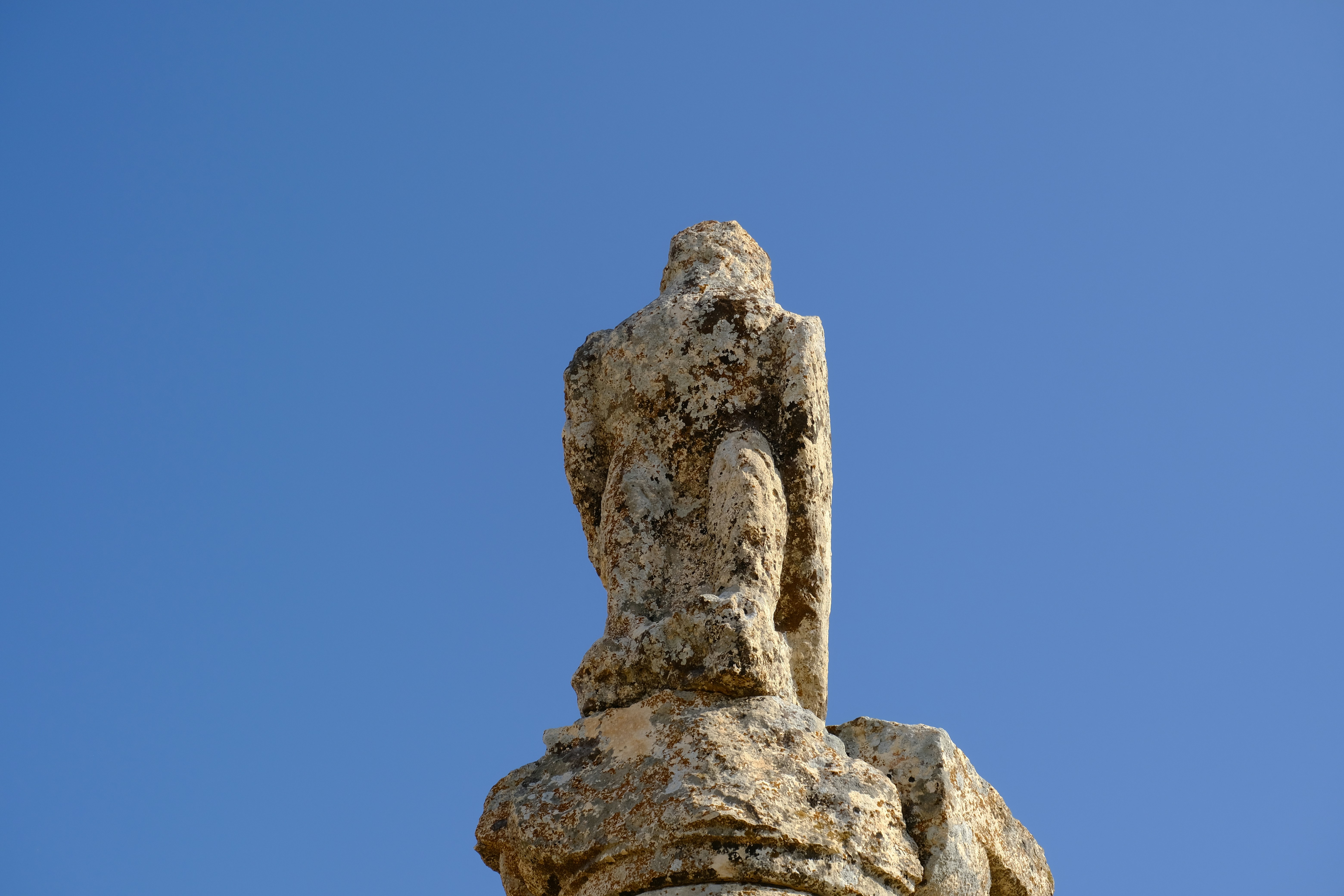 A stone sculpture stands against a blue sky.