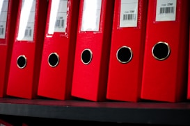 Red file folders are neatly arranged on a shelf.