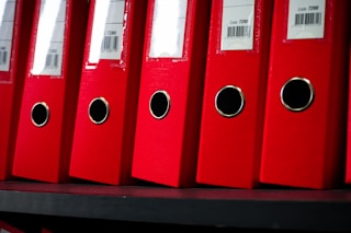 Red file folders are neatly arranged on a shelf.
