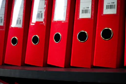 Red file folders are neatly arranged on a shelf.