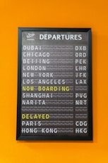 An airport departure board displays flight information.