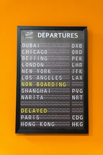 An airport departure board displays flight information.