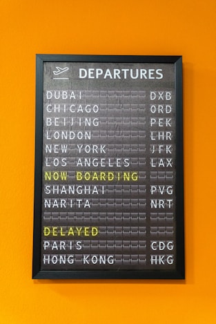 An airport departure board displays flight information.