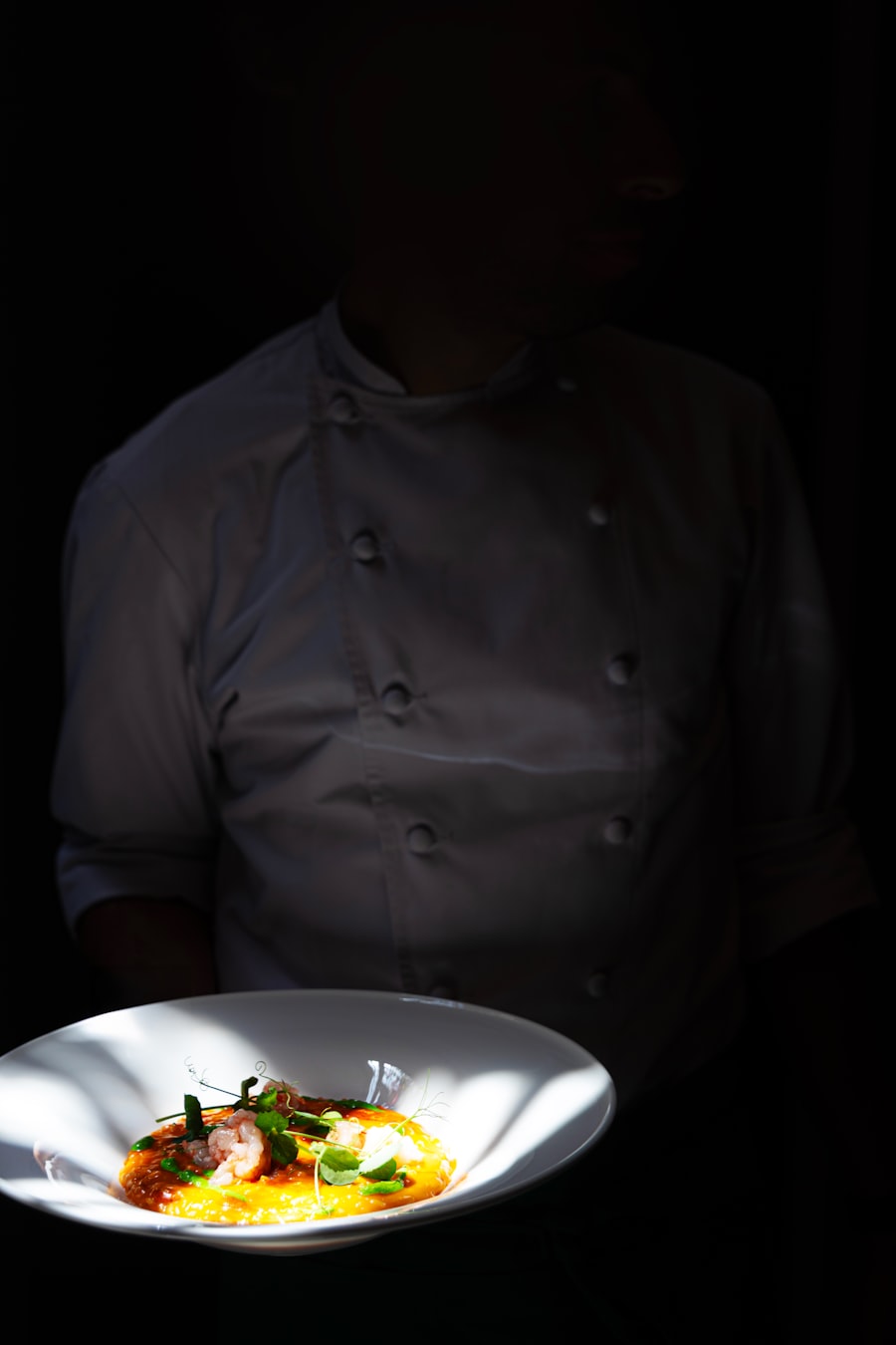 Chef dressant une assiette de poisson au restaurant Le Marchand