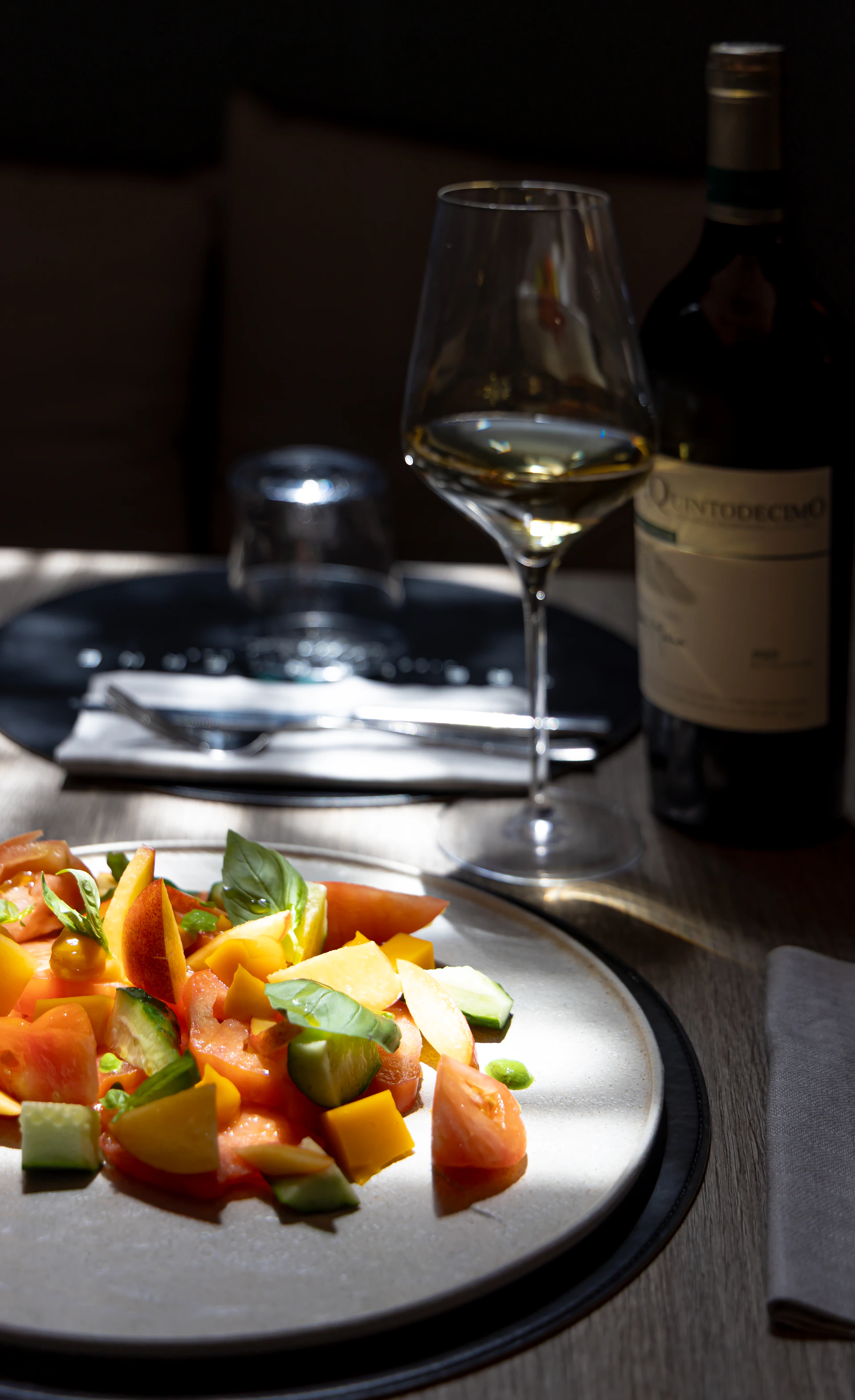 Fresh salad, wine, and a bottle on a table.