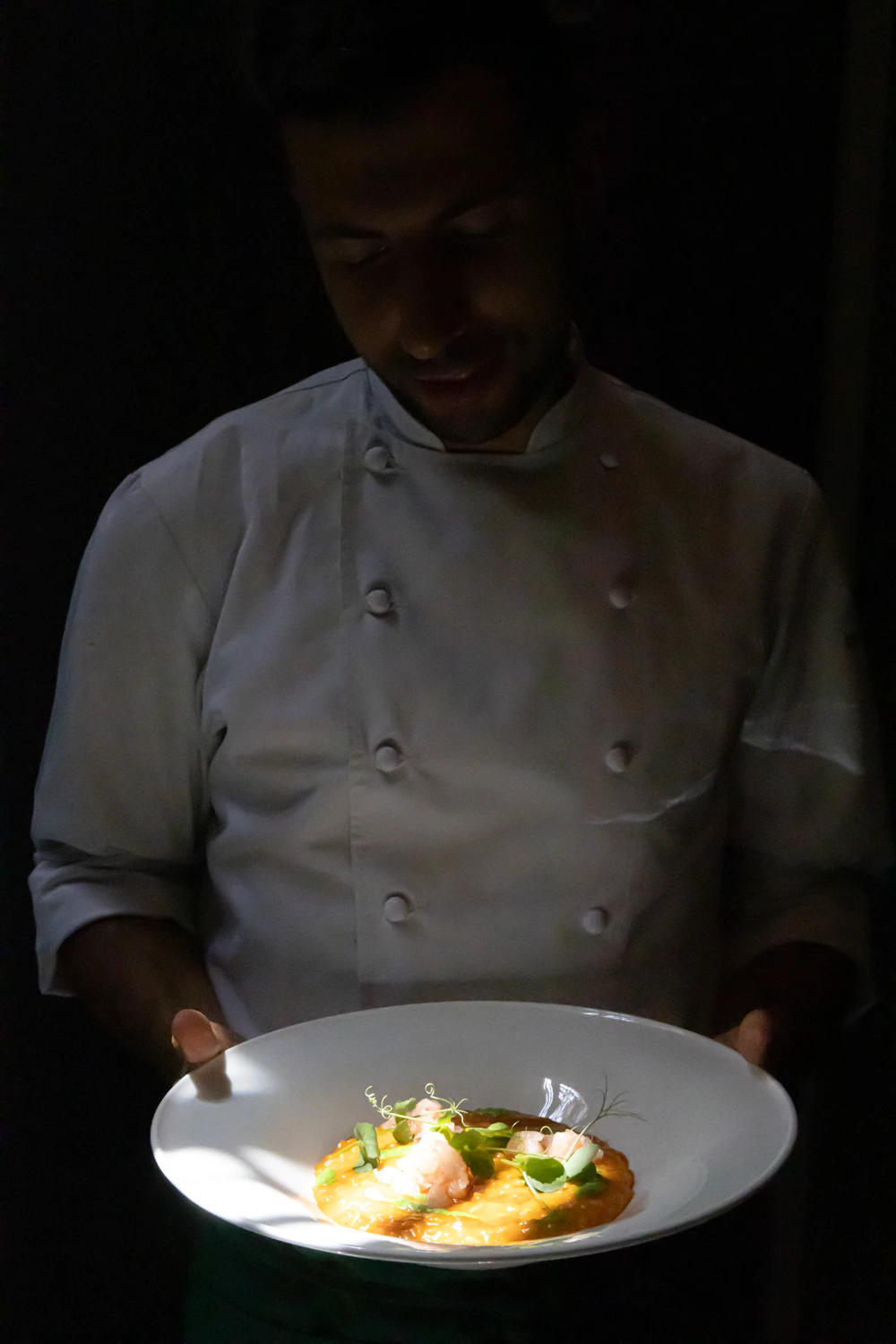 Chef's hands plating a dish with tweezers at AURELIA
