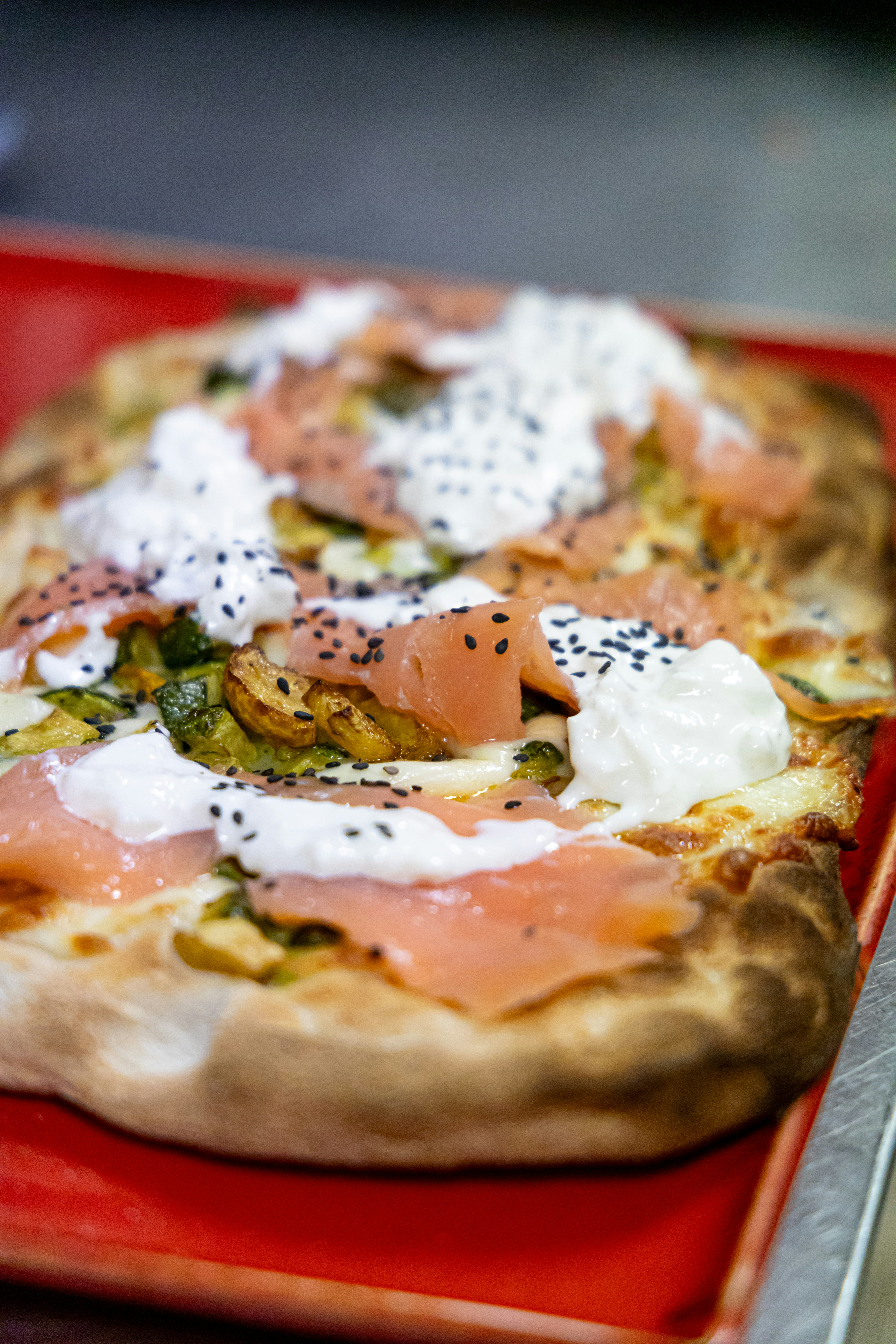 Smoked salmon flatbread with white cream cheese, black sesame seeds, and grilled vegetables`