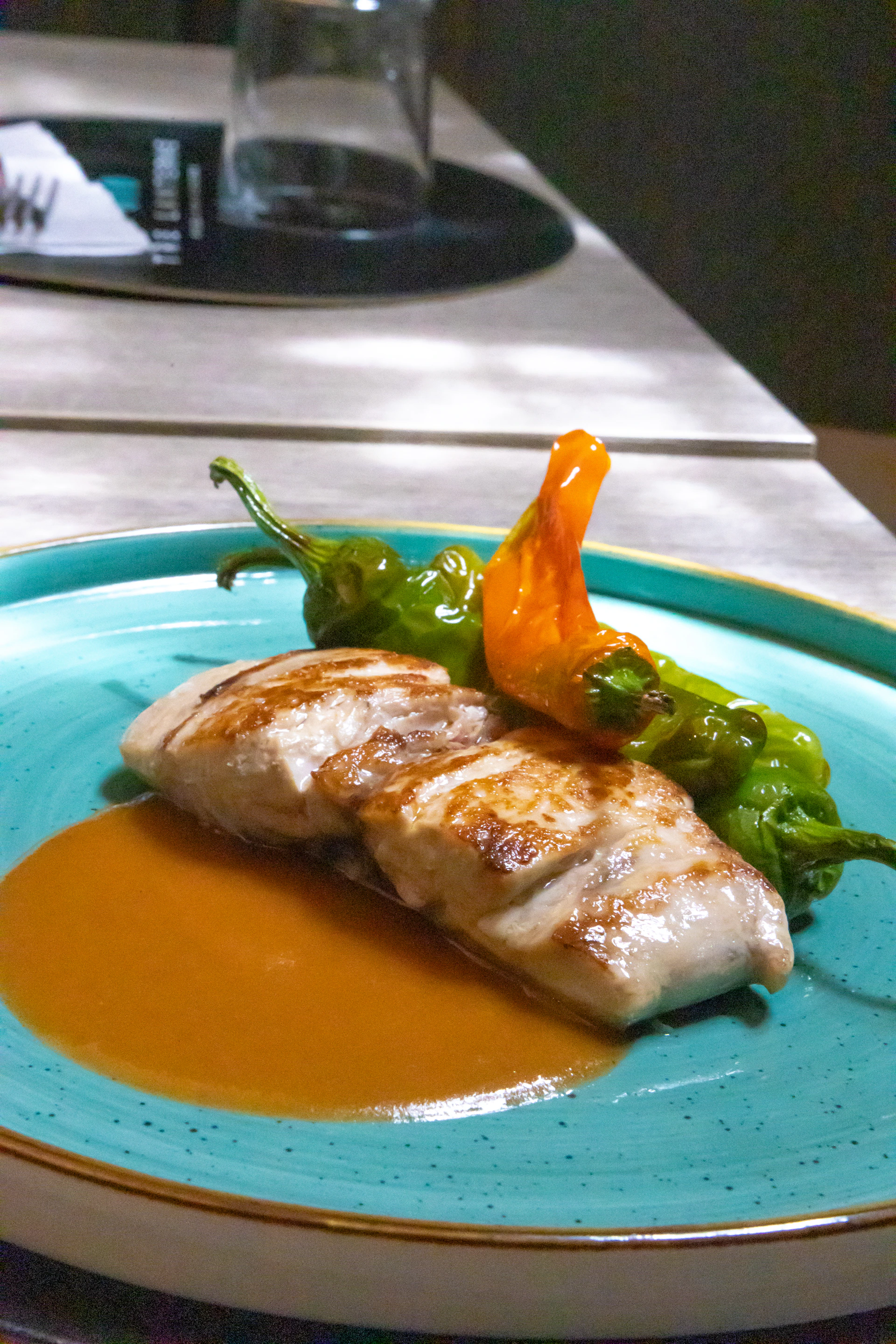 Grilled fish and peppers sit on a plate.