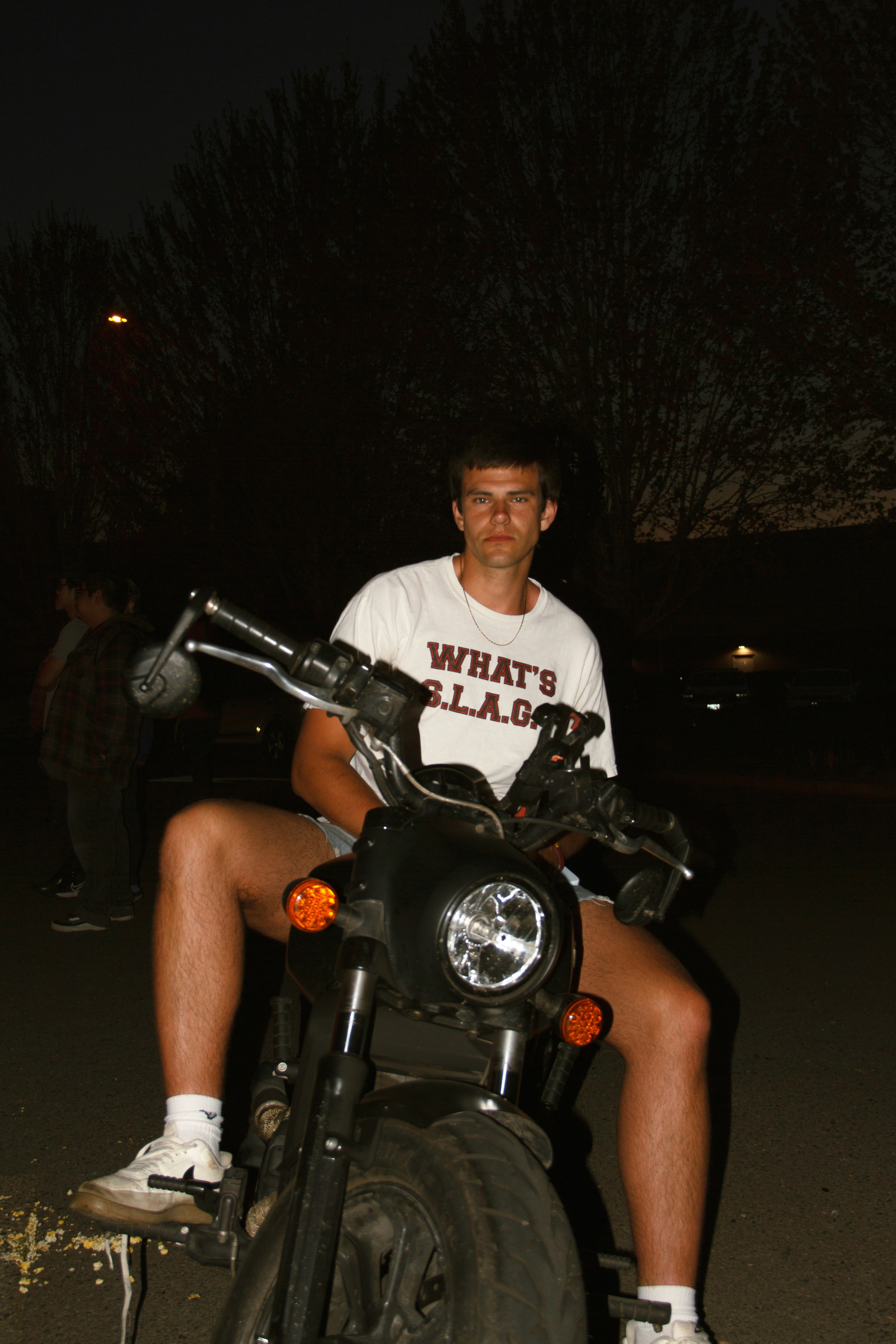 Man sits on a motorcycle at night.