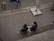 Two people sit on a bench, viewed from above.