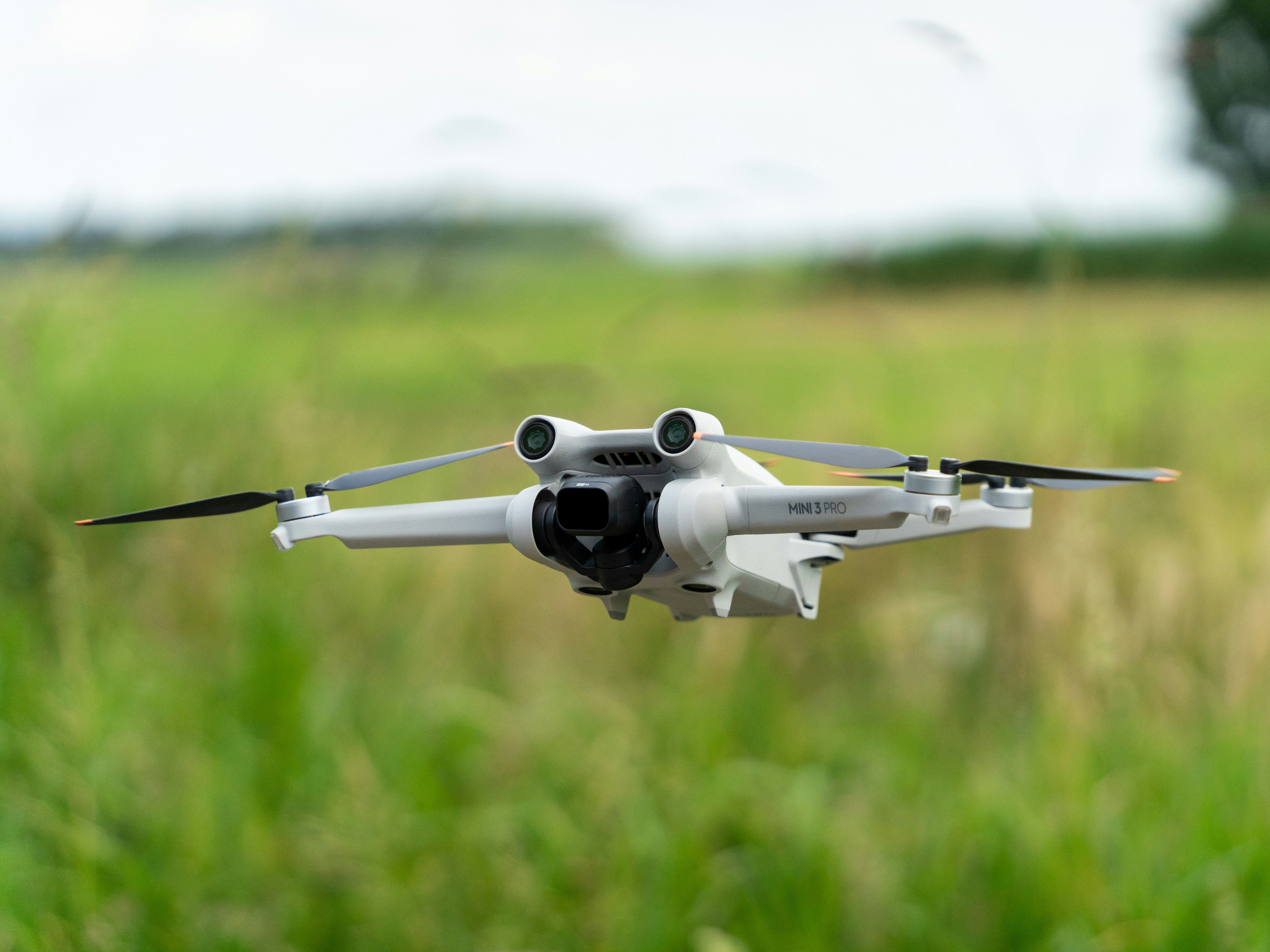 A drone is shown mid-flight over grass.
