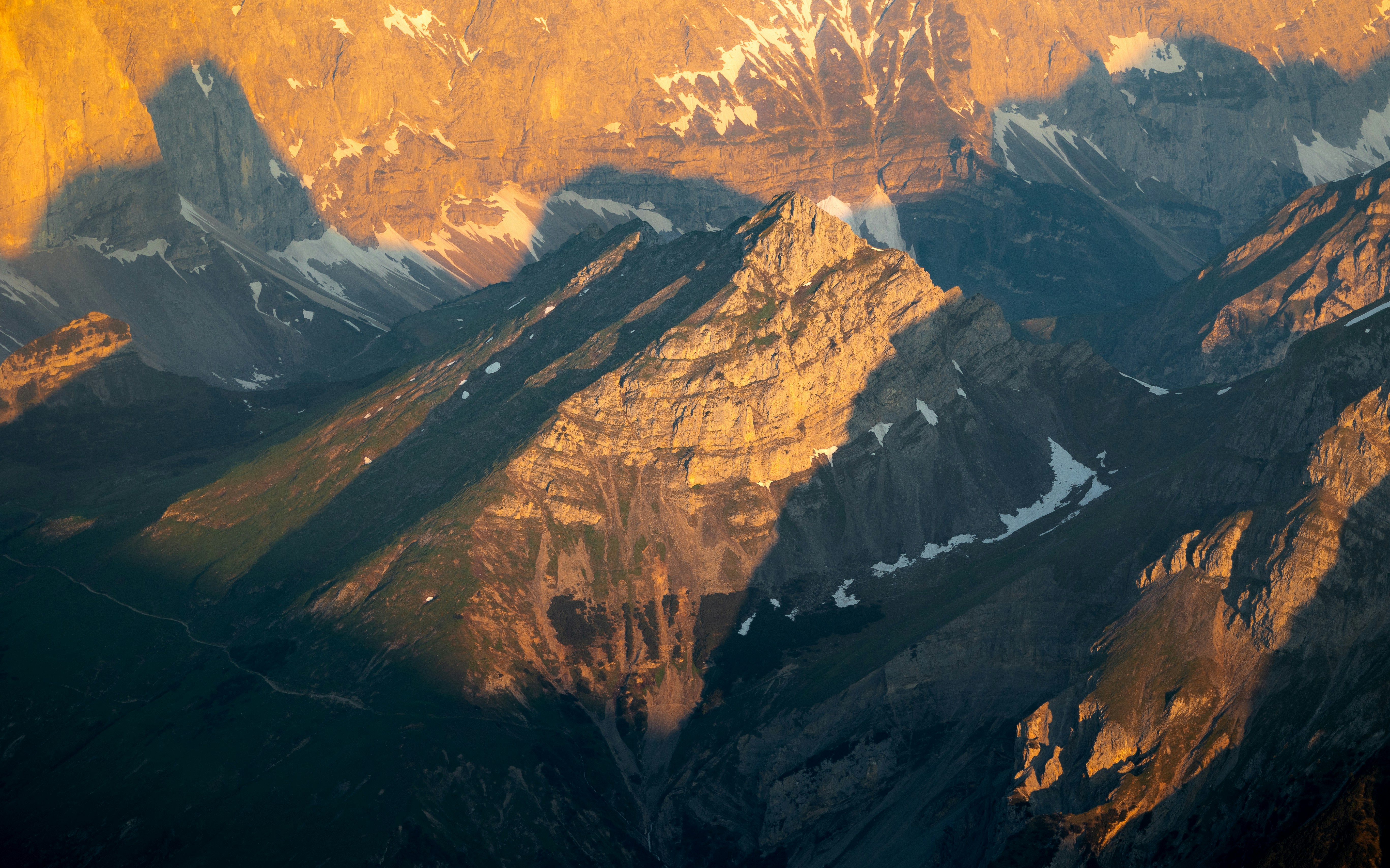 Sunlight bathes majestic mountains with shadows.
