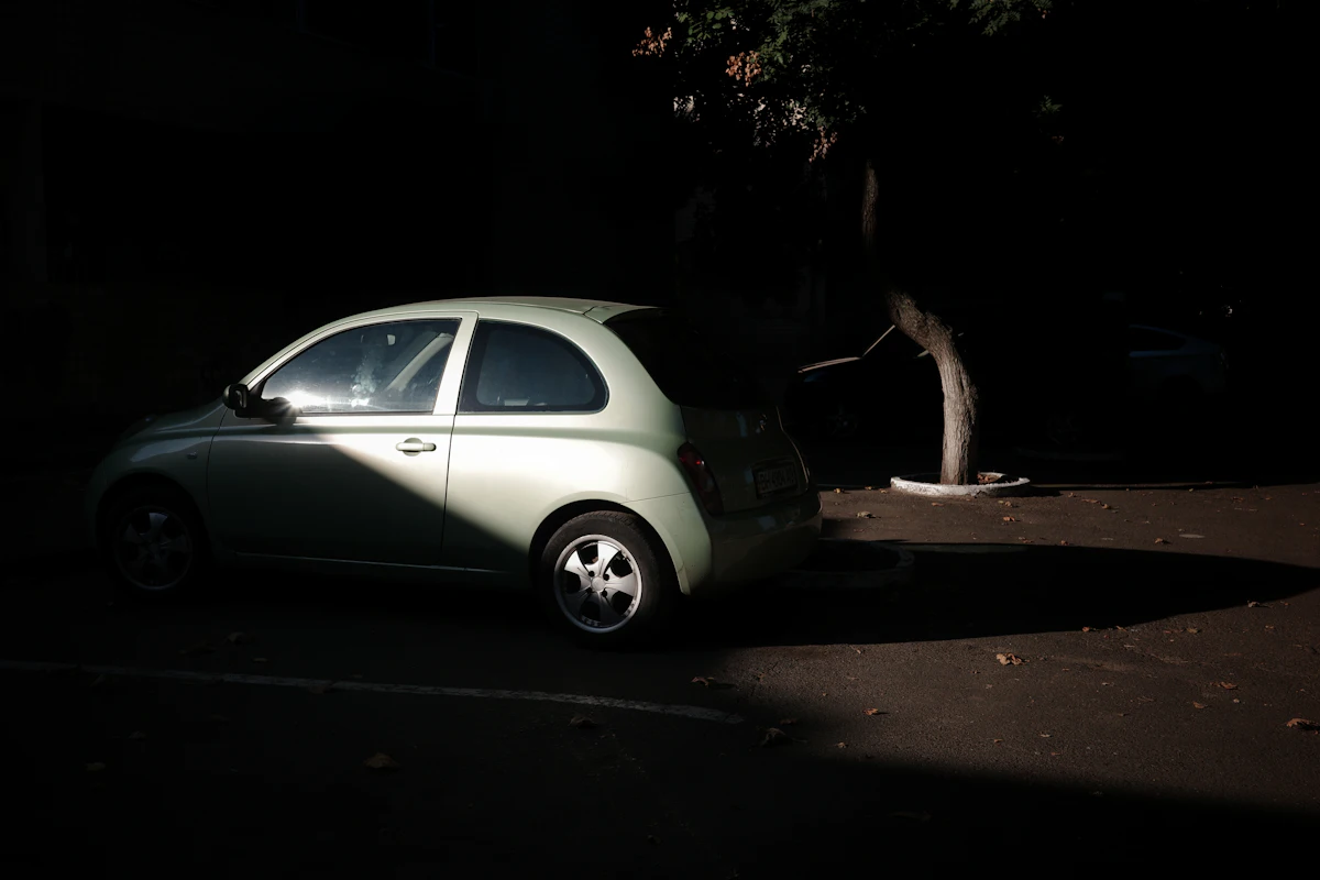 A small hatchback parked alone in a pool of light at night
