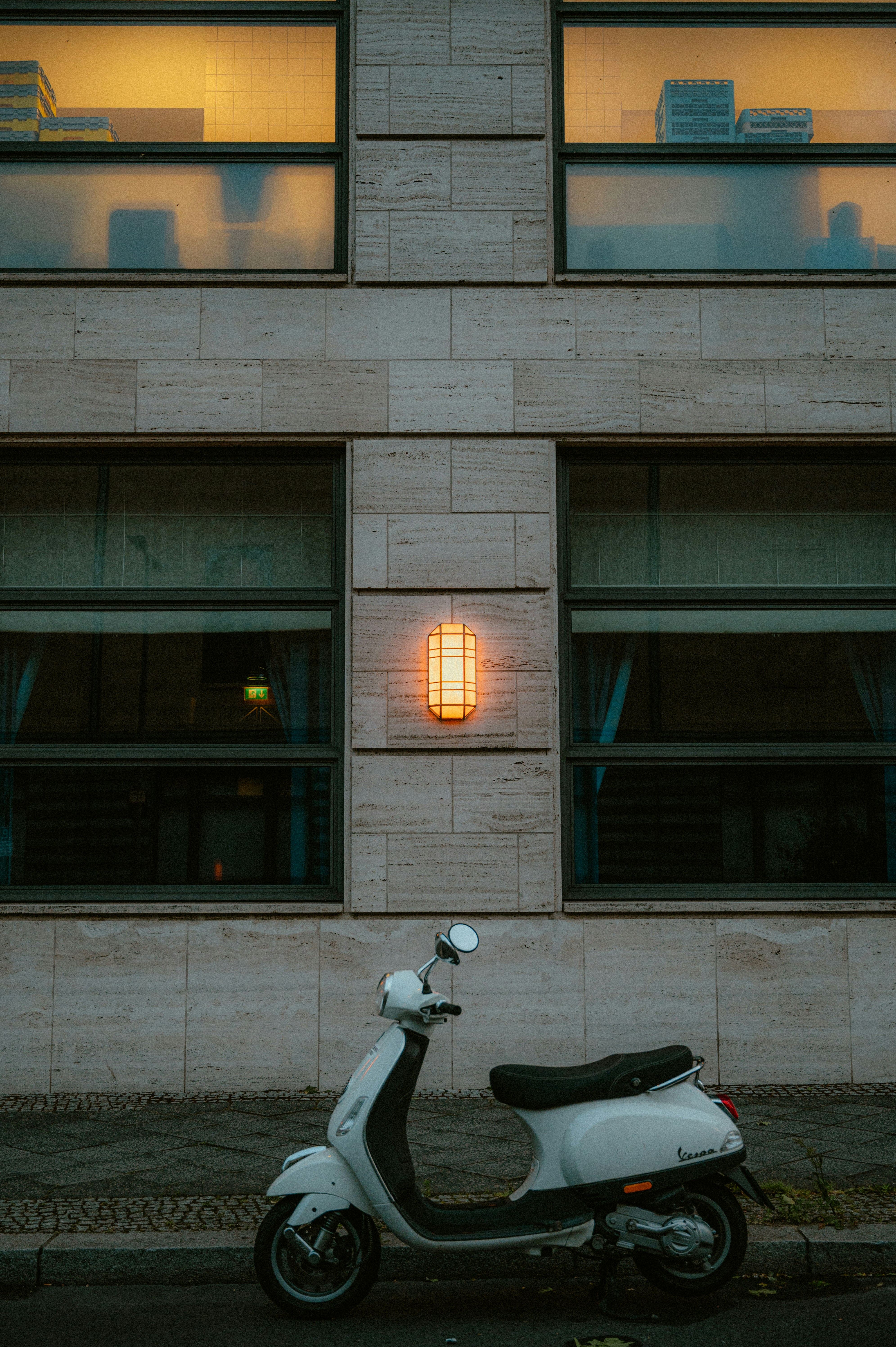 A white scooter parks in front of a building.