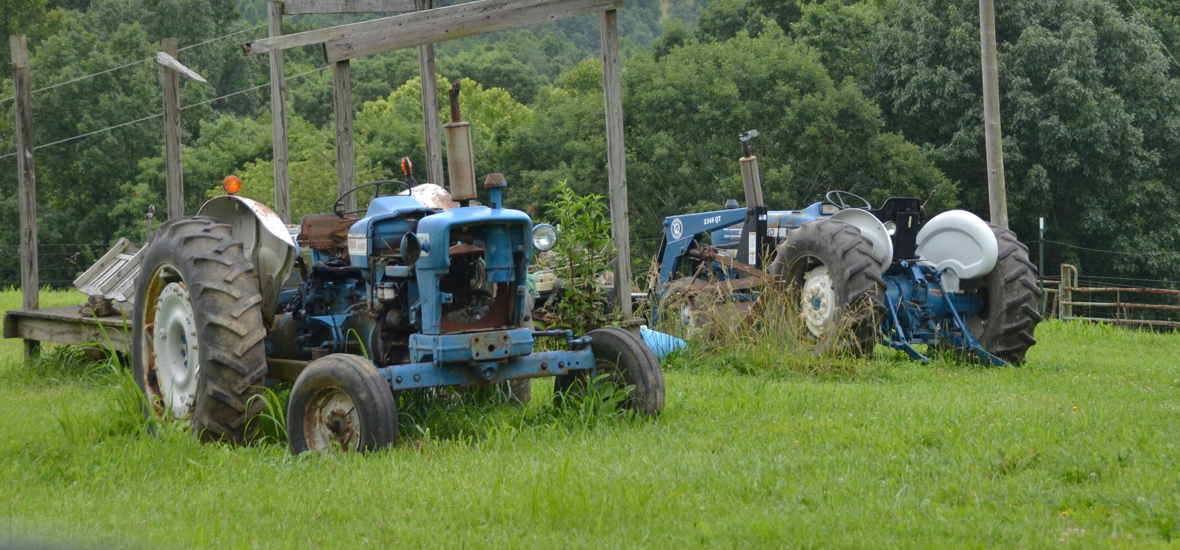A compact tractor with a front-end loader attachment working on a small farm