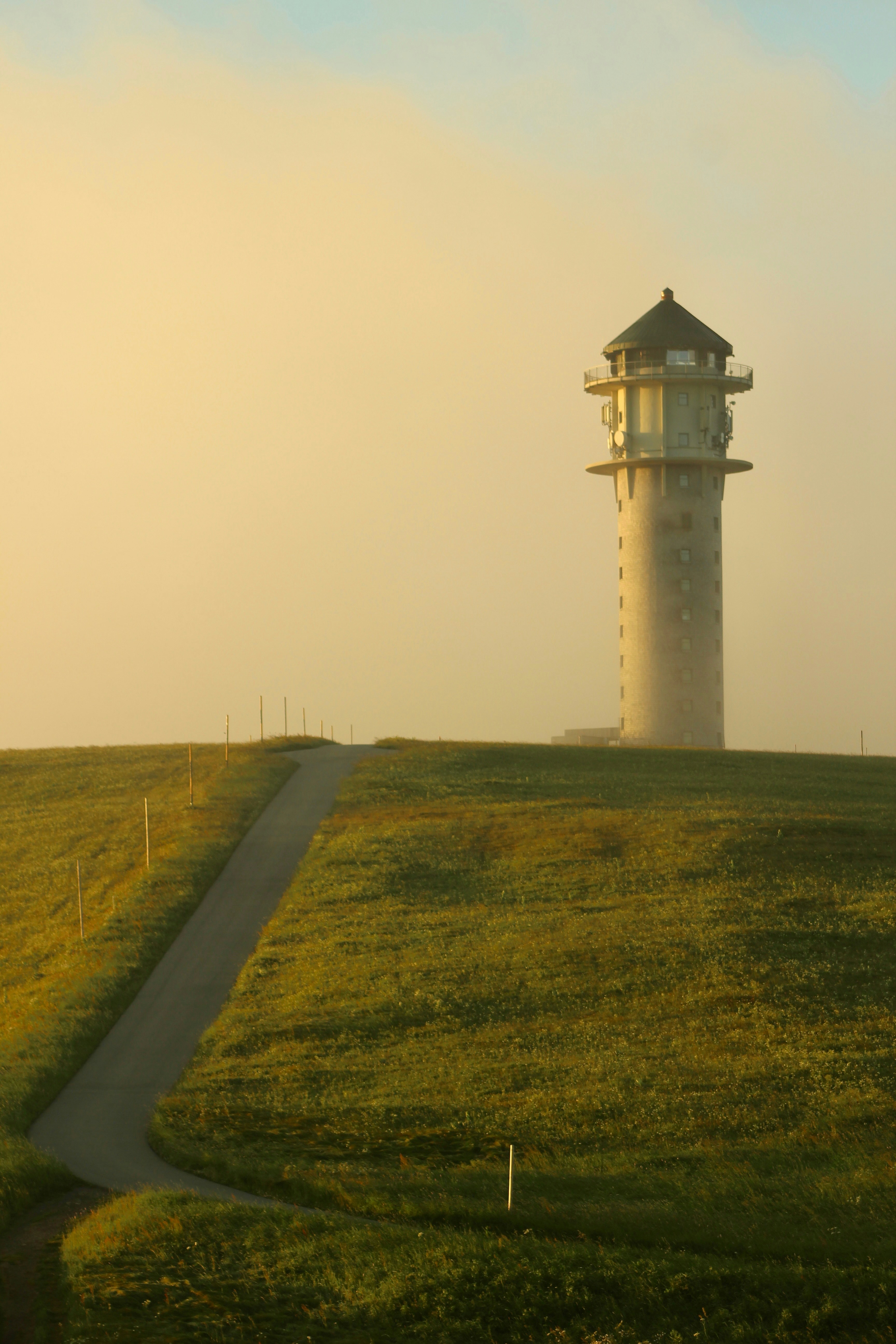 A tower stands atop a grassy hill.