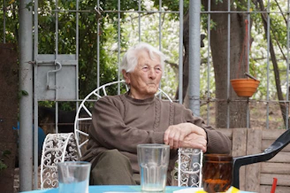 An elderly woman sits outside, relaxing.