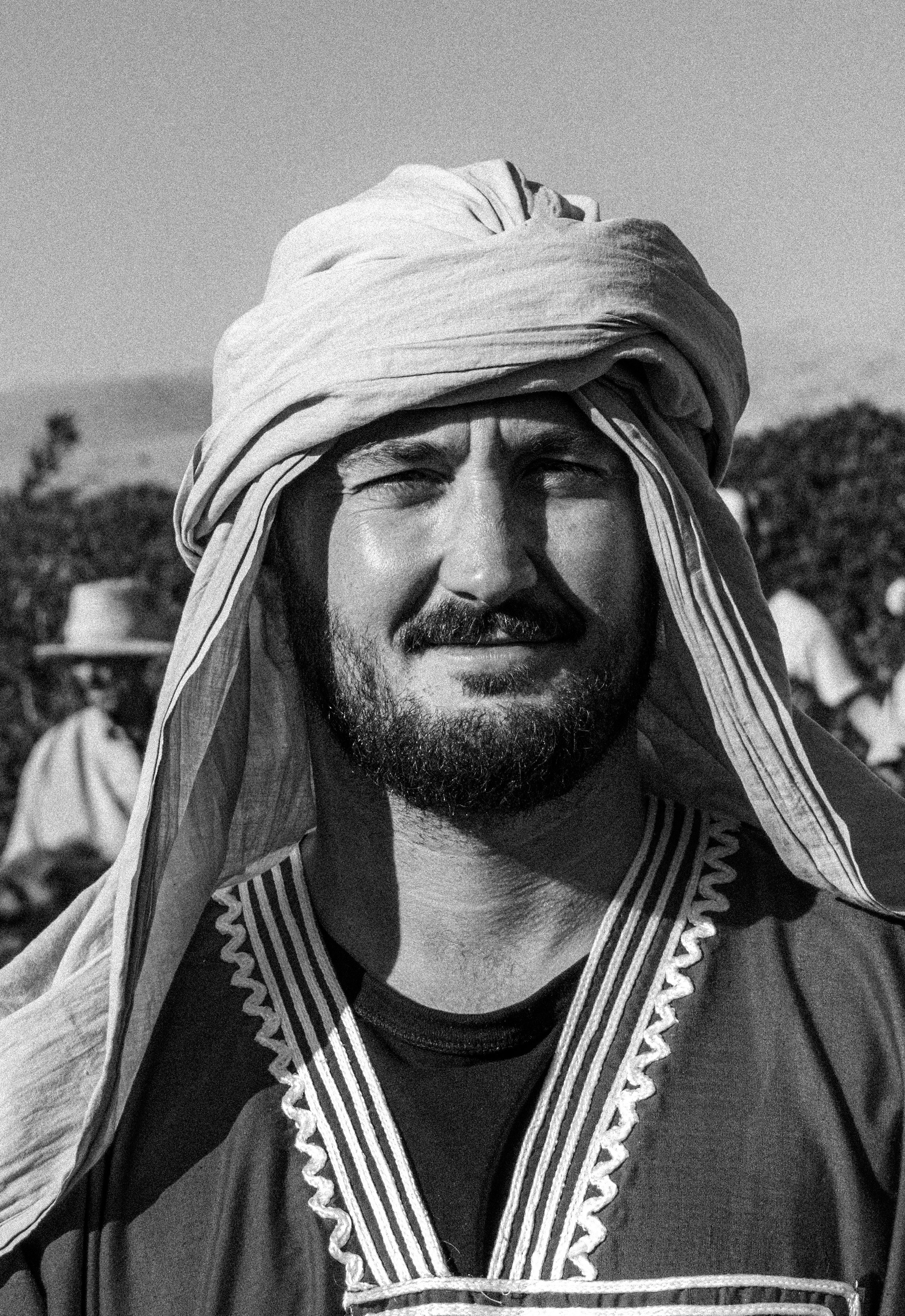 A man wears a turban and looks directly.