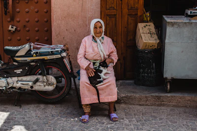 Elderly woman holding a cat in a street.