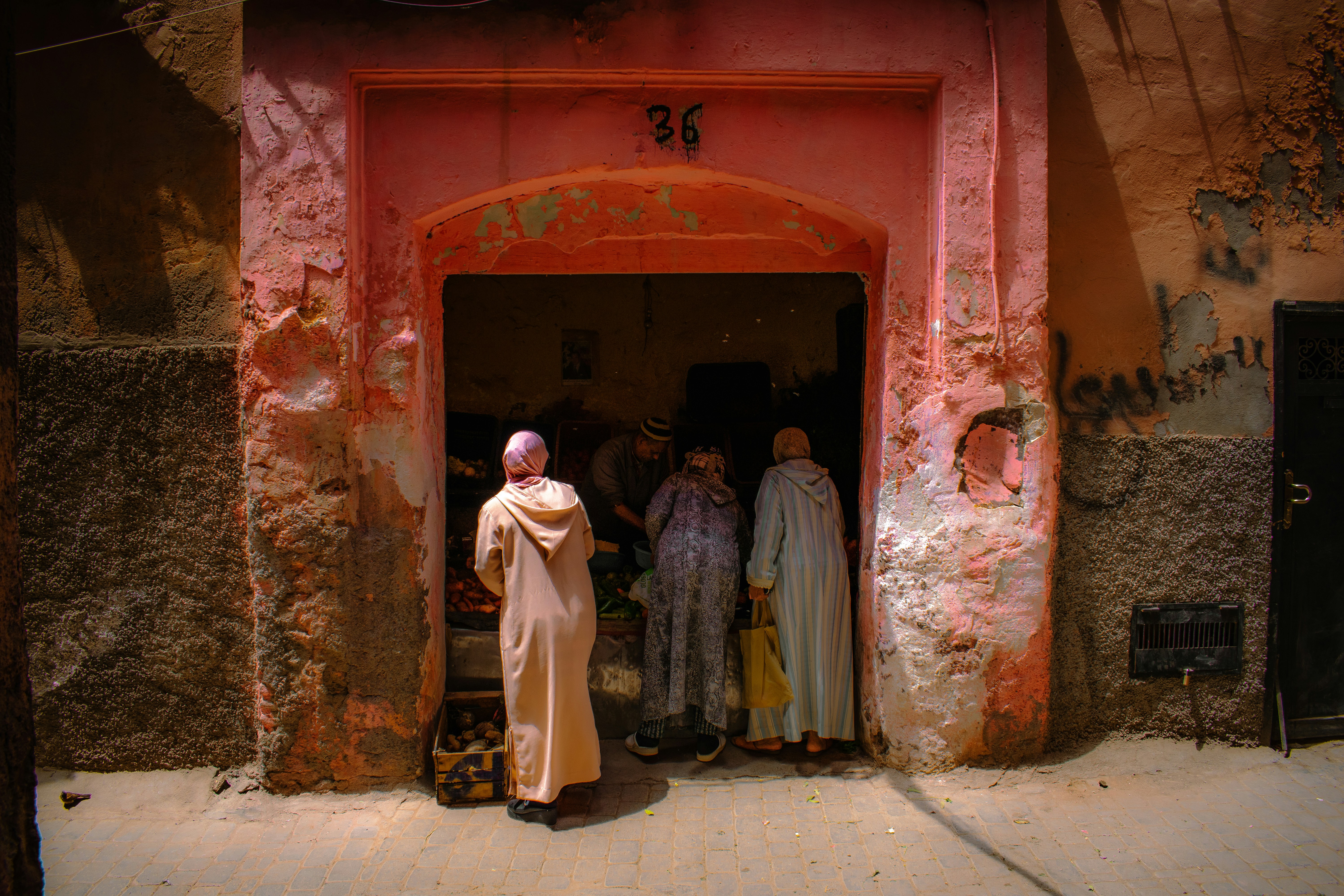 Thousands of women gathered in an open field, cooking pongala in earthen pots over small fires, with the Attukal Bhagavathy Temple visible in the background.