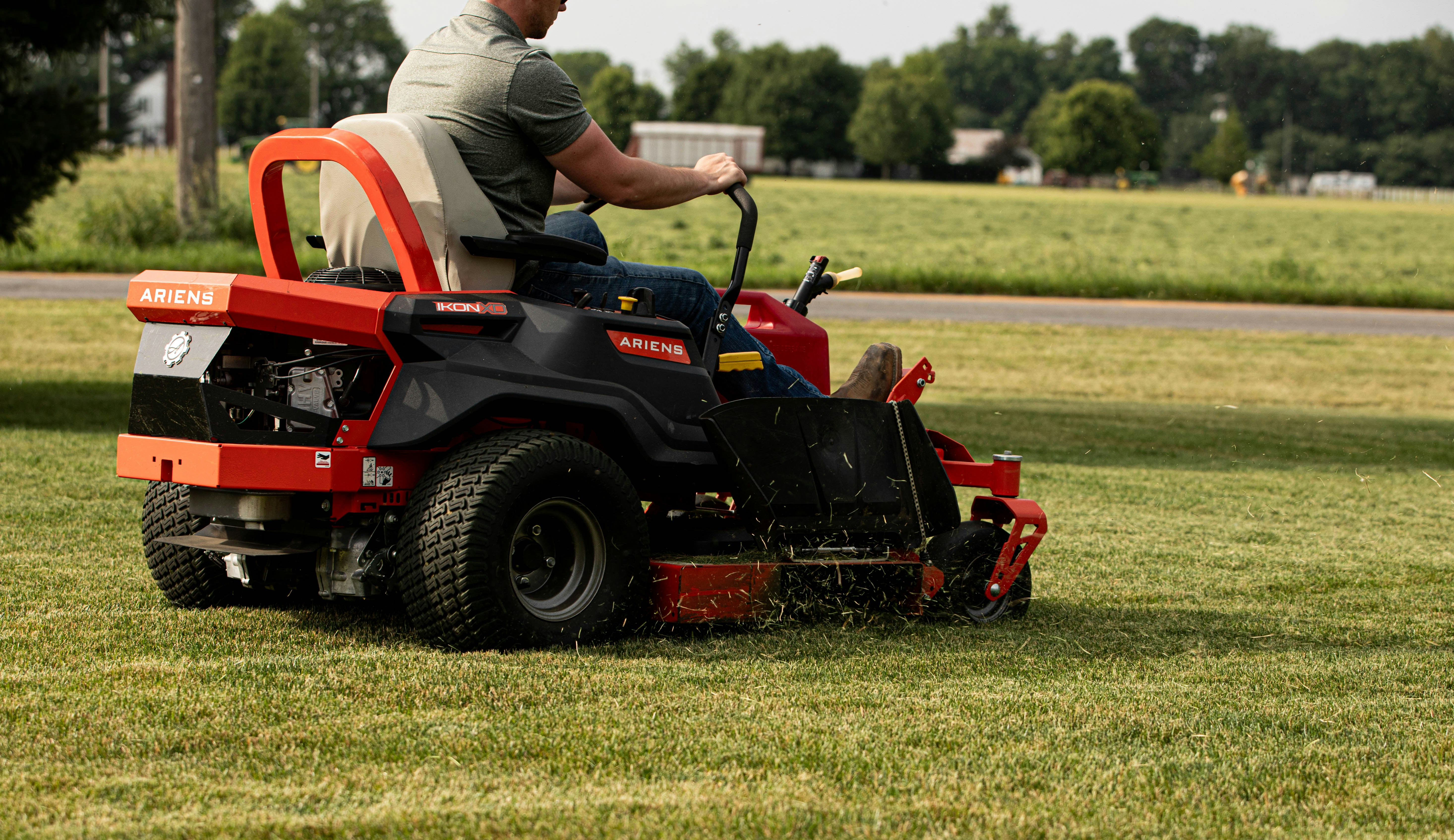 A man mows the lawn with a riding mower.