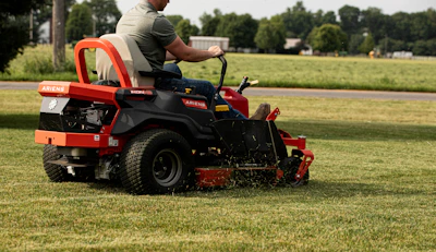 A man mows the lawn with a riding mower