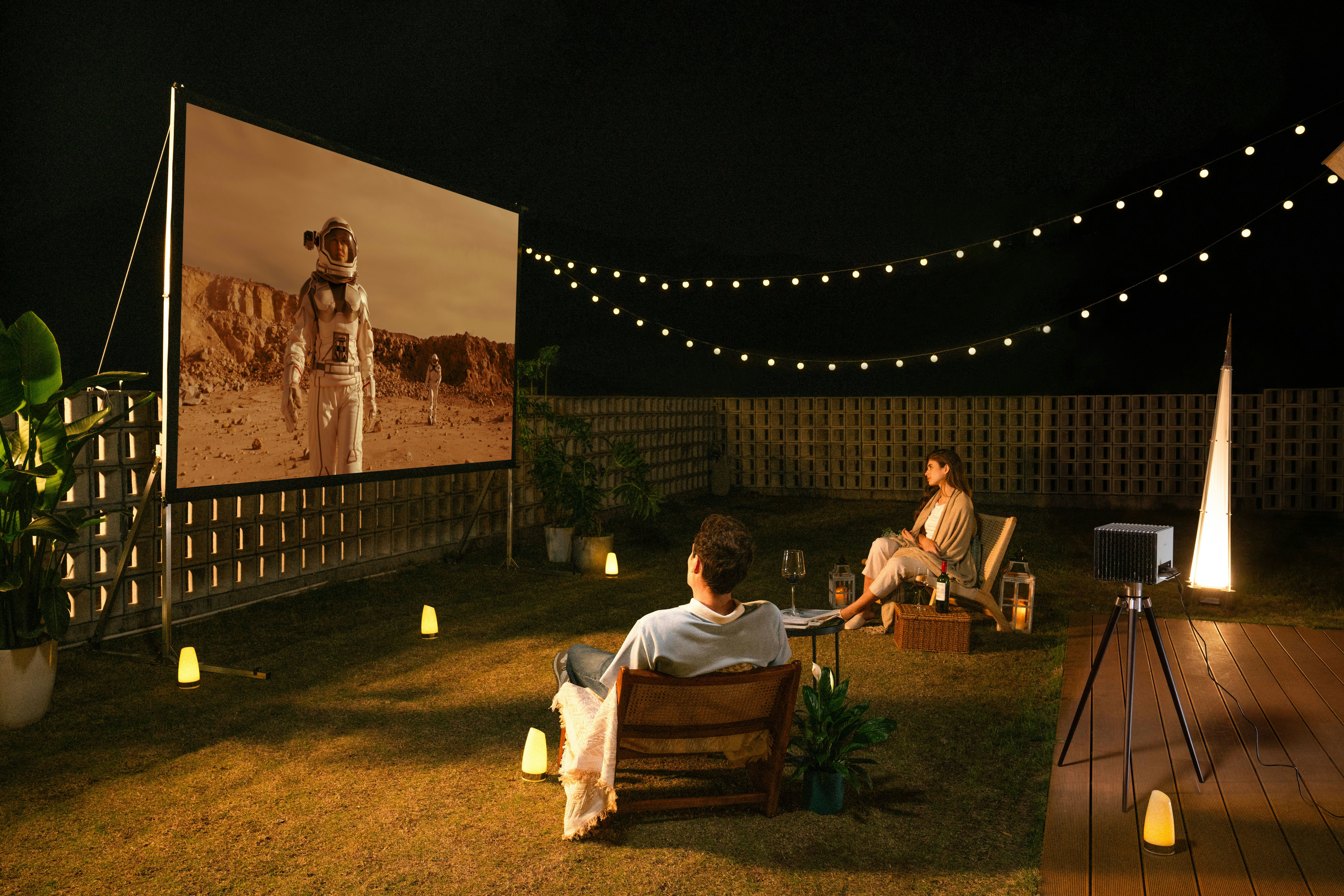 Valerion projector beams a sci‑fi astronaut scene onto backyard screen under starry sky.