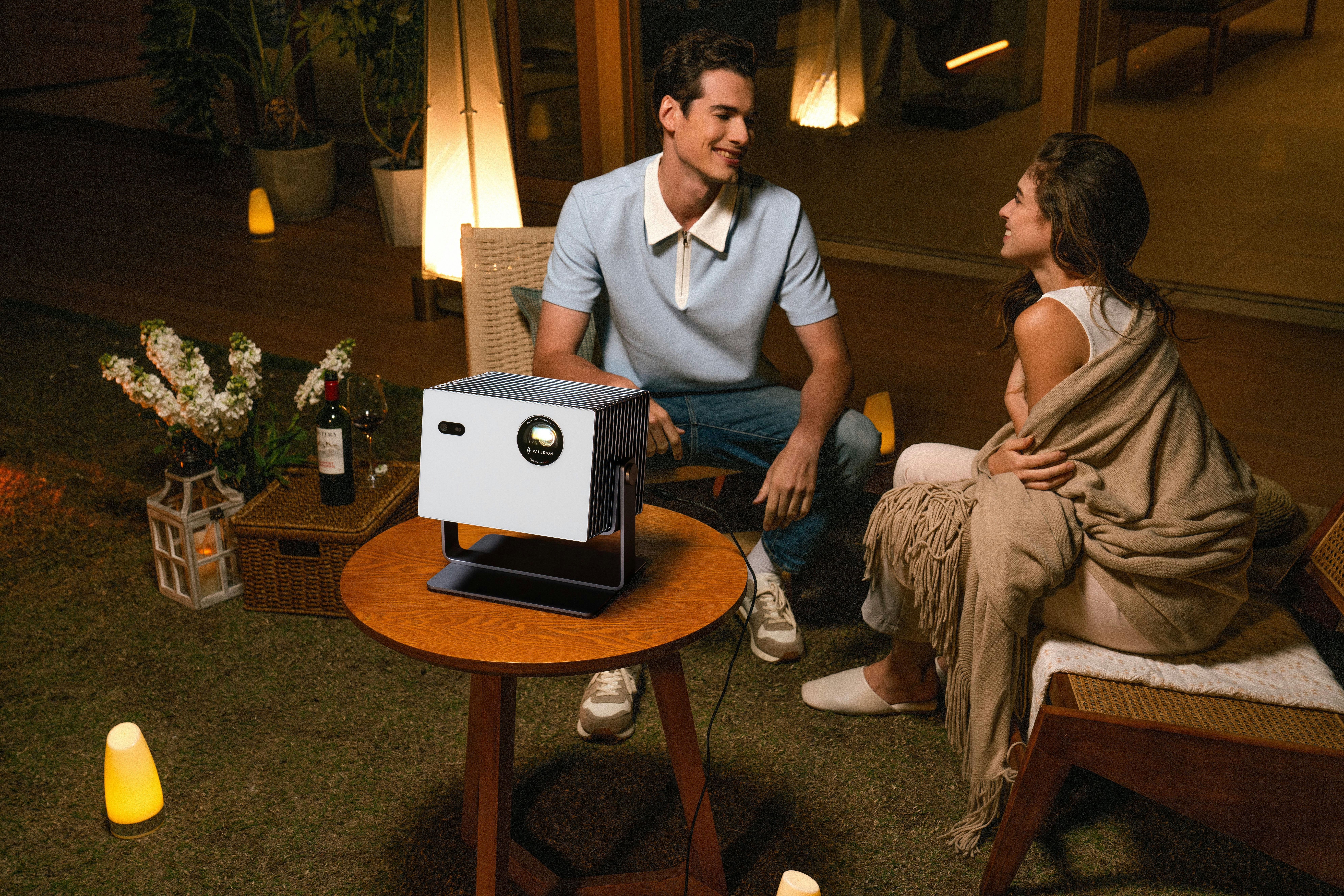 A couple enjoys a movie night outdoors with a projector.