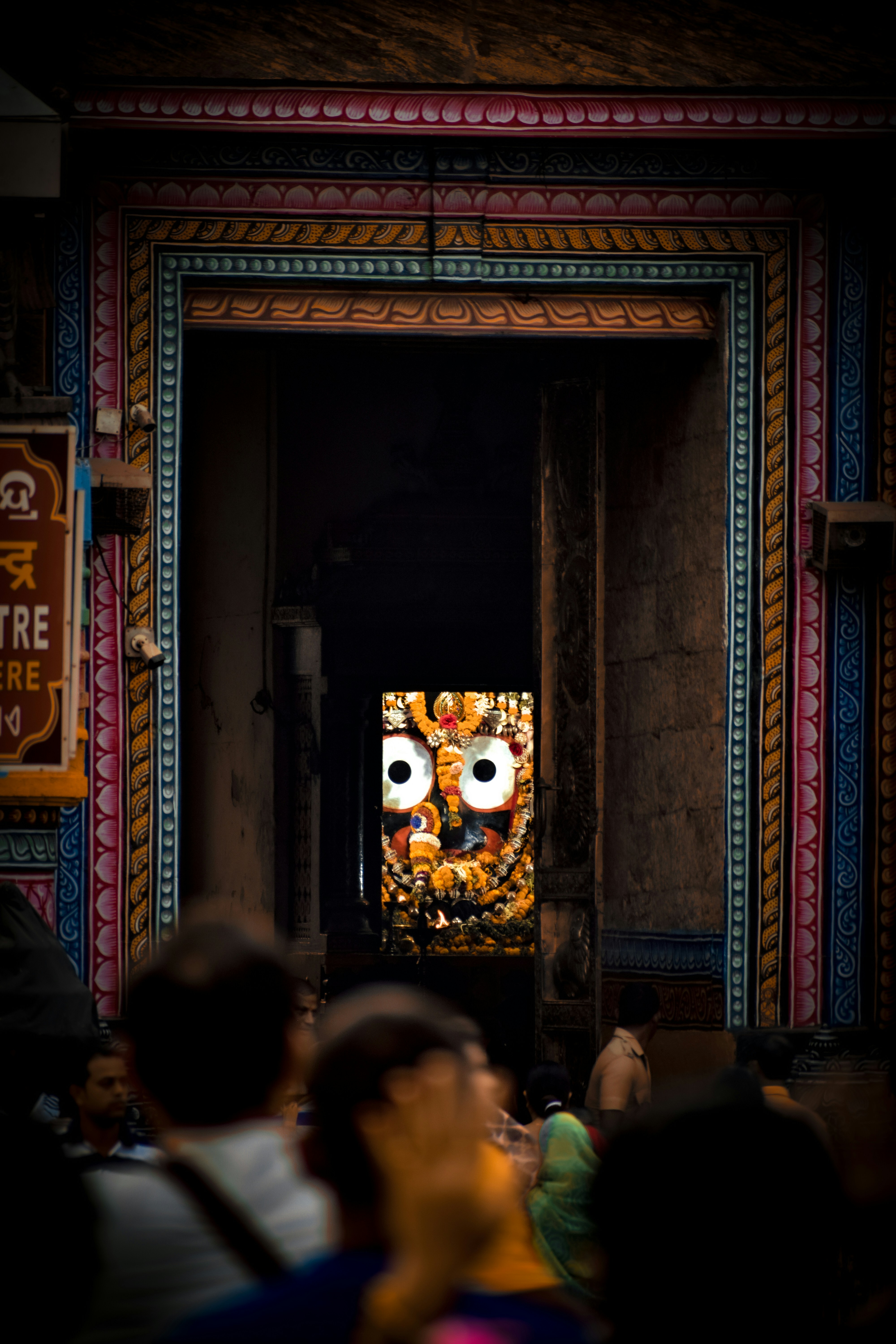 People gaze at a deity through an arched doorway