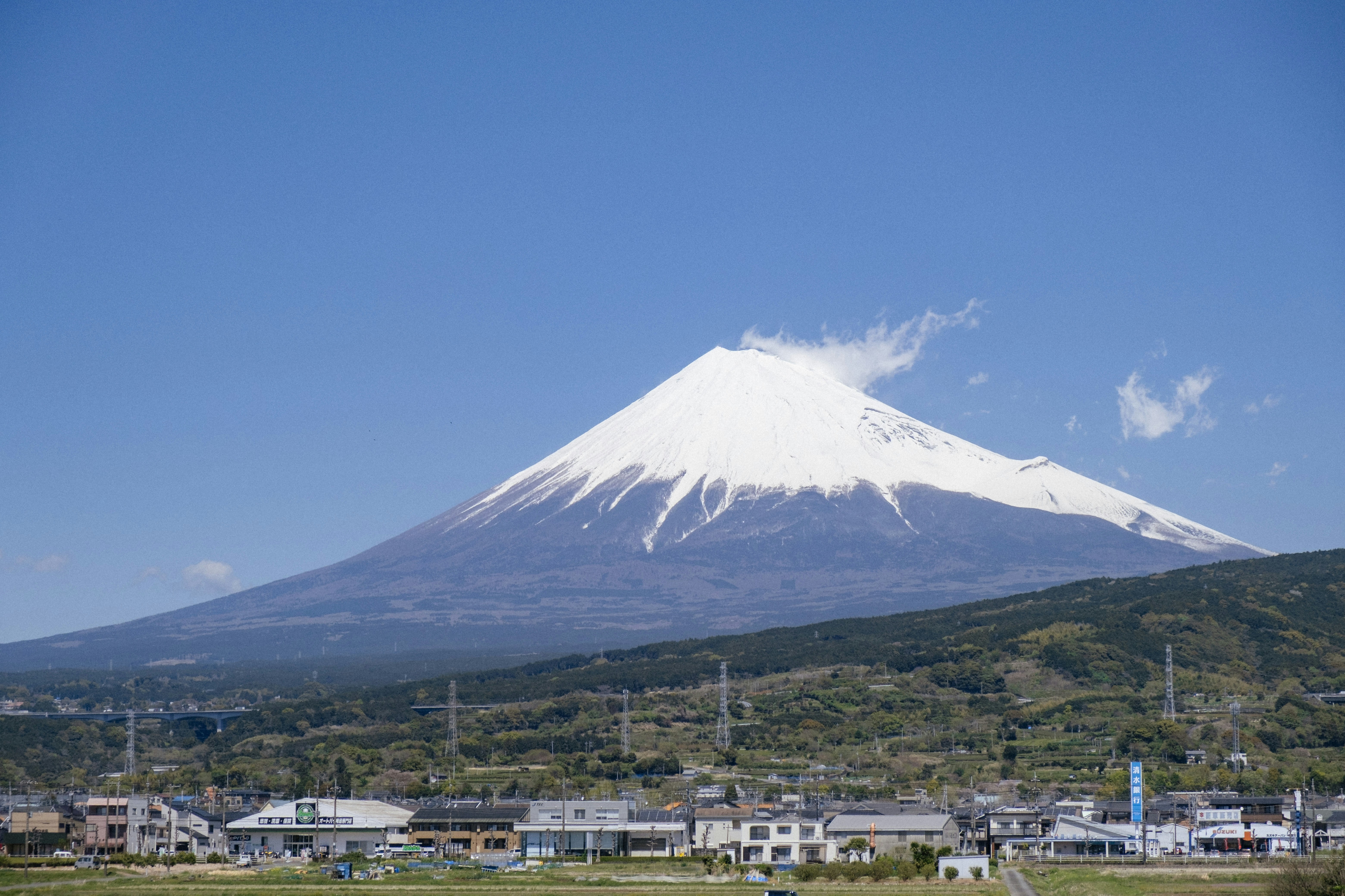 Mount fuji towers over a small town., 