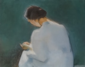 A woman is reading a book, facing away.